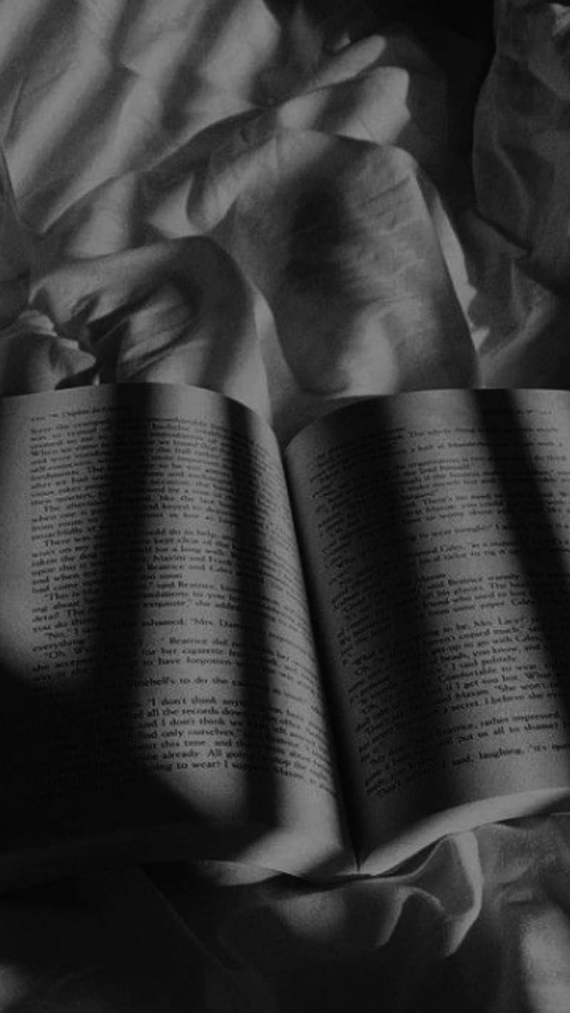 An open book on a bed with the sheets in disarray. - Shadow