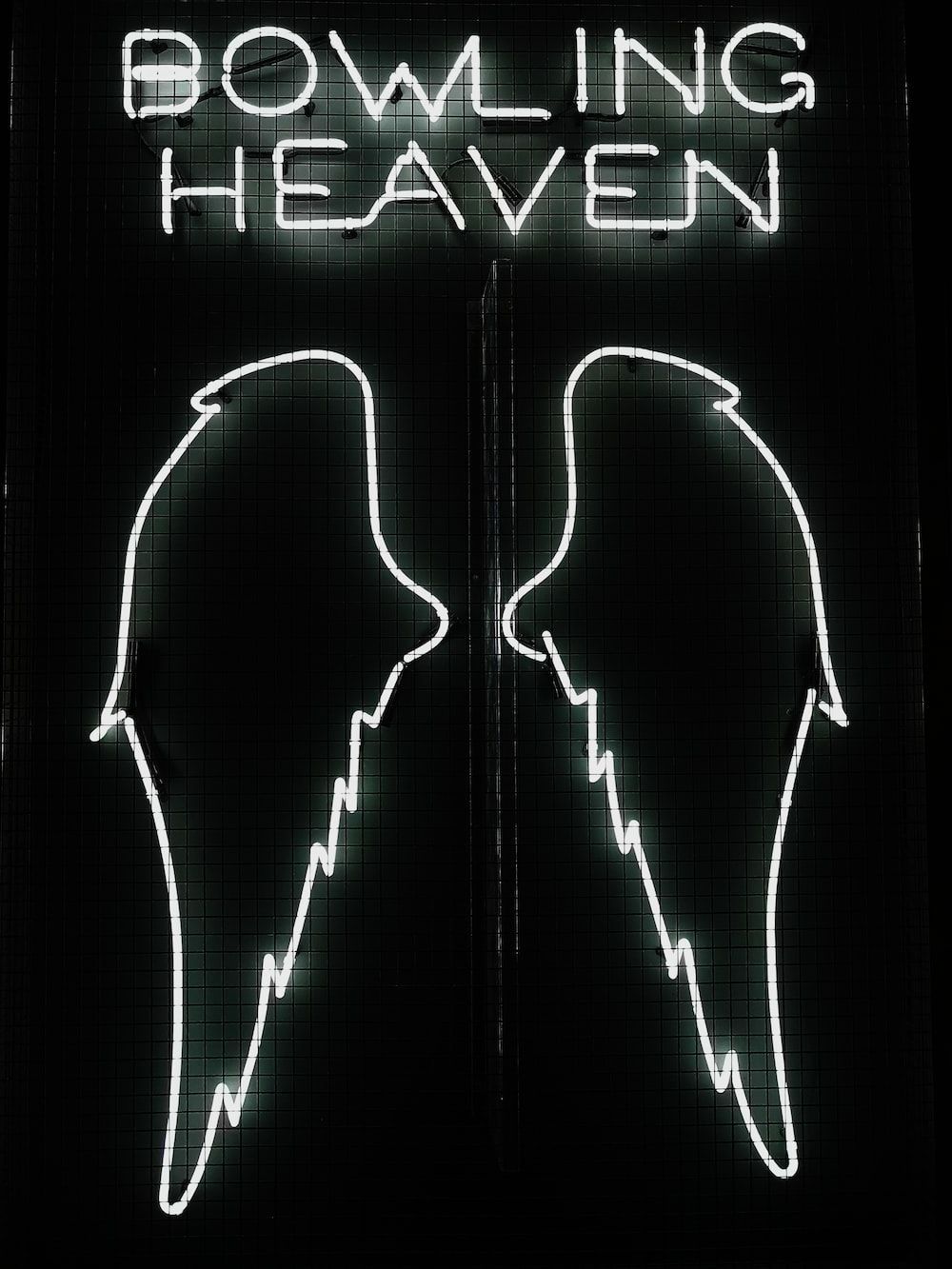 A neon sign with two wings and the words Bowling Heaven. - Wings