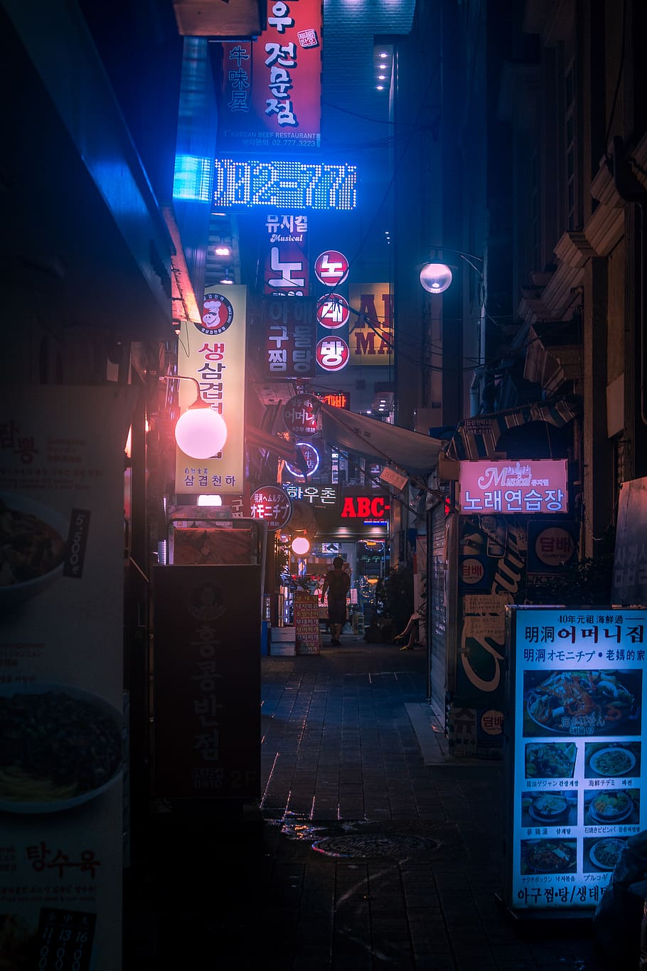 A street at night with neon signs and advertisements. - Seoul