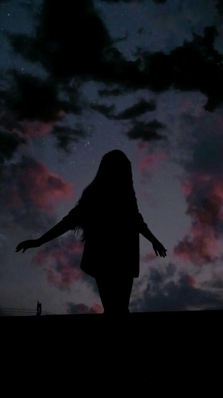 Silhouette of a girl with her arms outstretched against a cloudy sky - Shadow