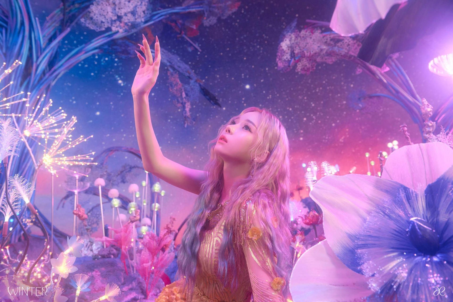 The image is a beautiful scene of a woman with pink hair dressed in a pink and gold dress, surrounded by flowers and lights. The image has a dreamy and fantasy aesthetic. - Aespa