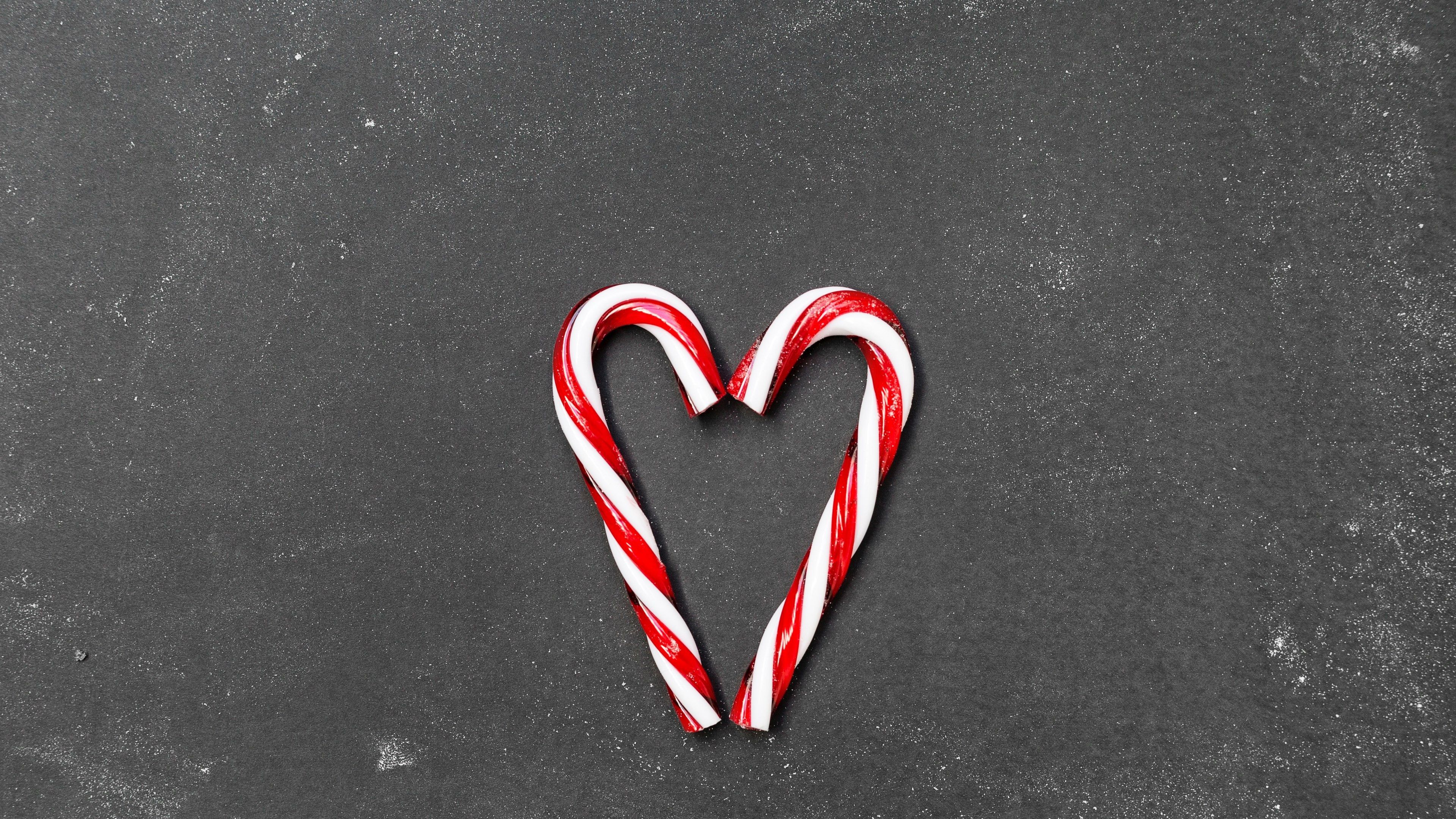 Two candy canes forming a heart shape on a black background - Candy cane