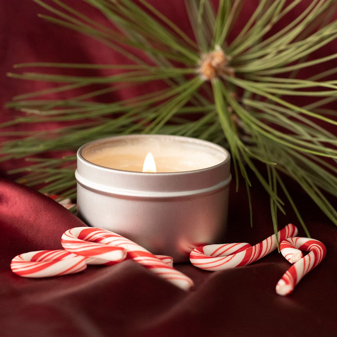 A candle and candy canes on top of red fabric - Candy cane