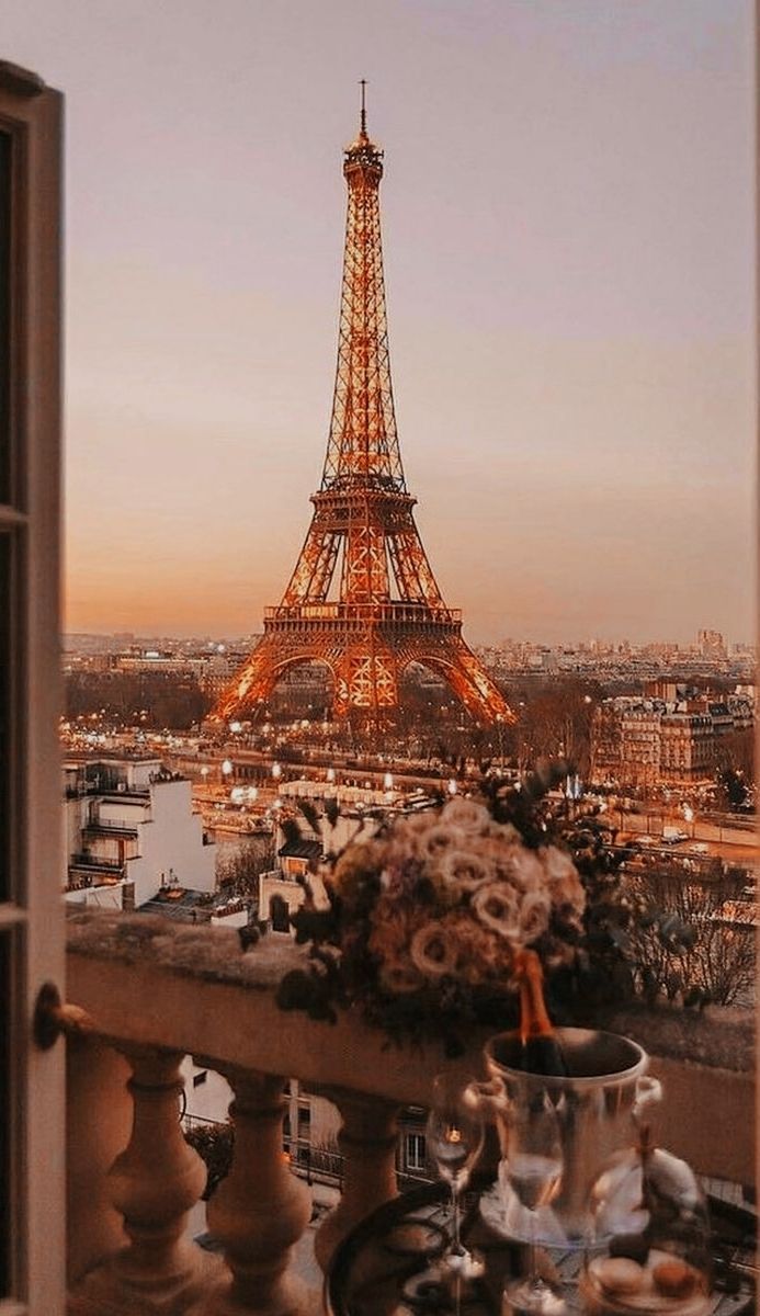 A balcony with a table, wine glasses and a vase with flowers. In the background, the Eiffel Tower. - Eiffel Tower, Paris