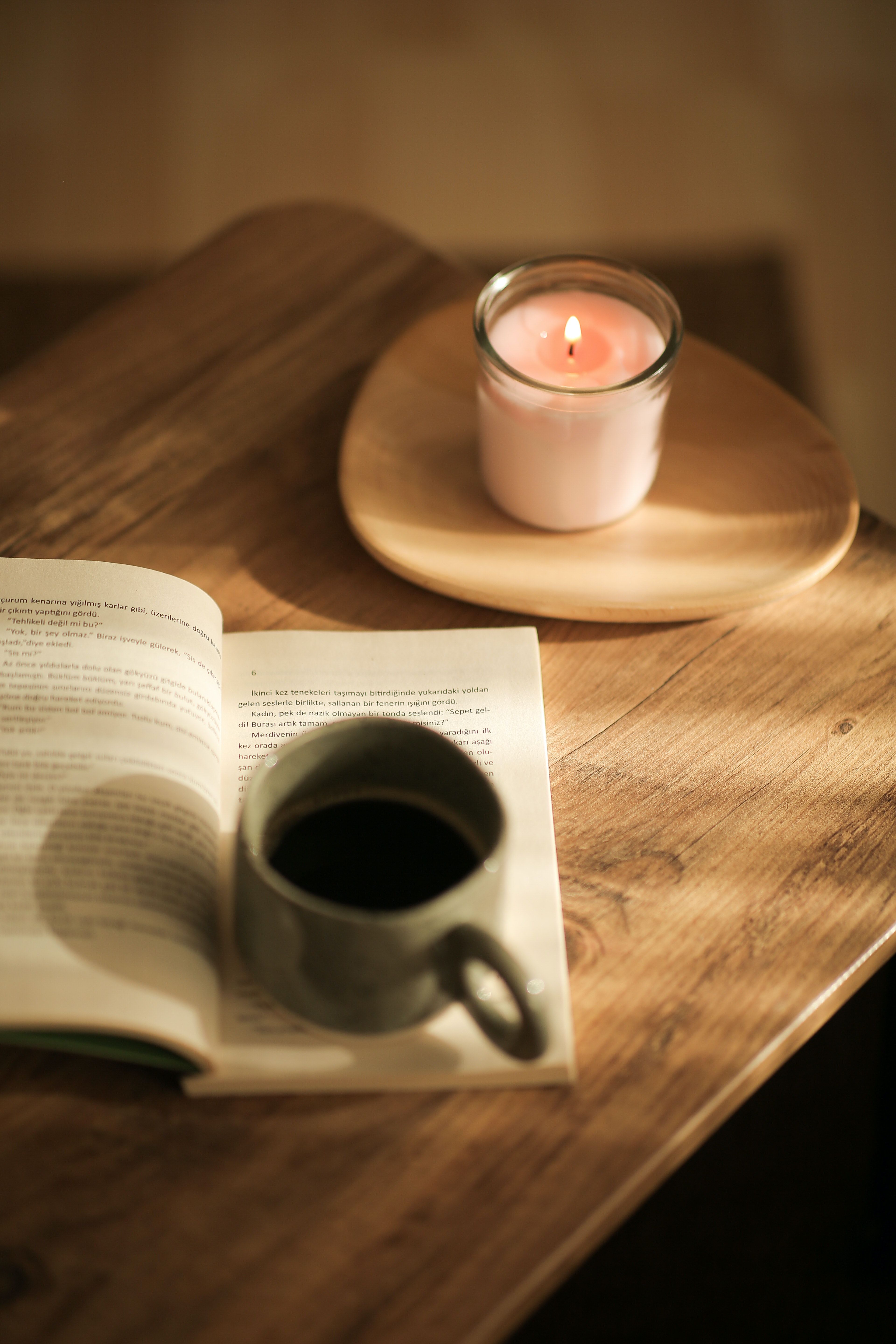A book, a cup of coffee, and a candle on a table. - Books