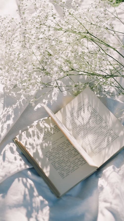 Open book on a white sheet with flowers - Books