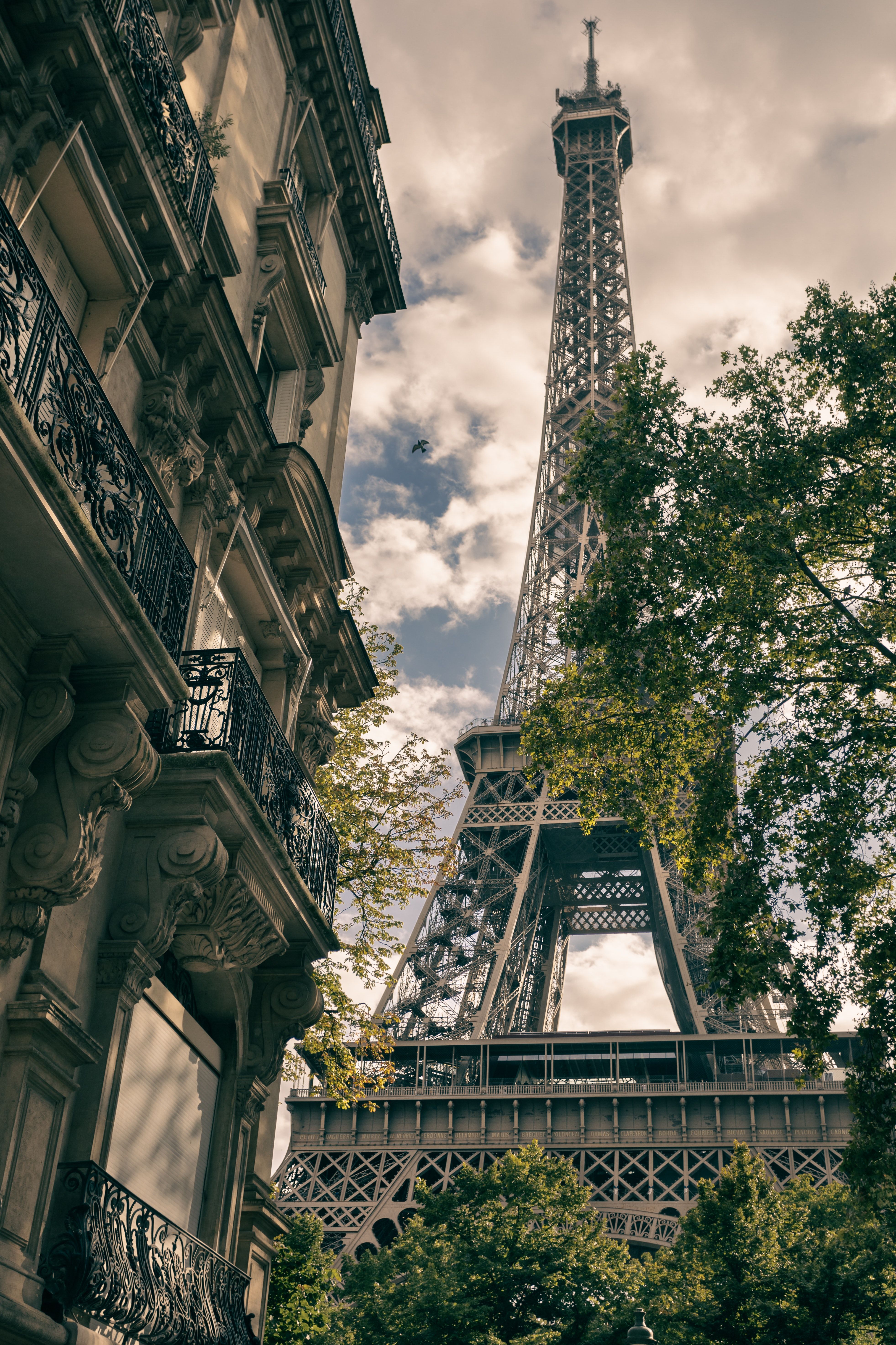 A tall building with trees and buildings in the background - Eiffel Tower