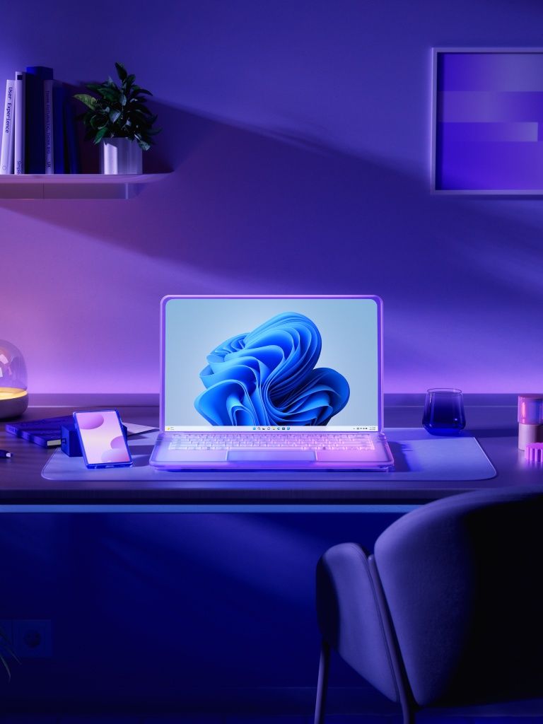 A laptop on a desk with a purple light in the background - Technology