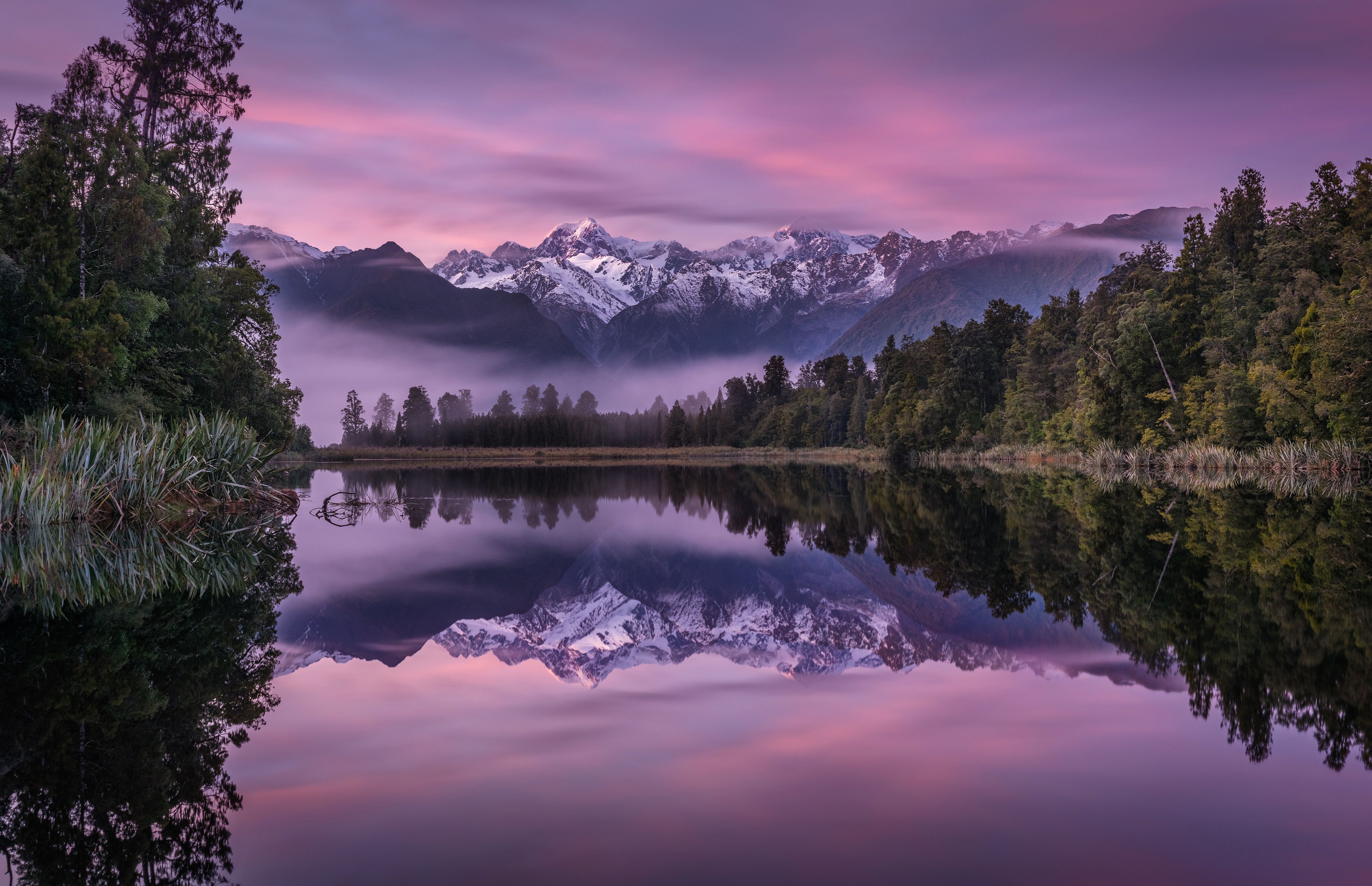 A stunning view of a mountain range and forest reflected in a lake at sunset. - Lake