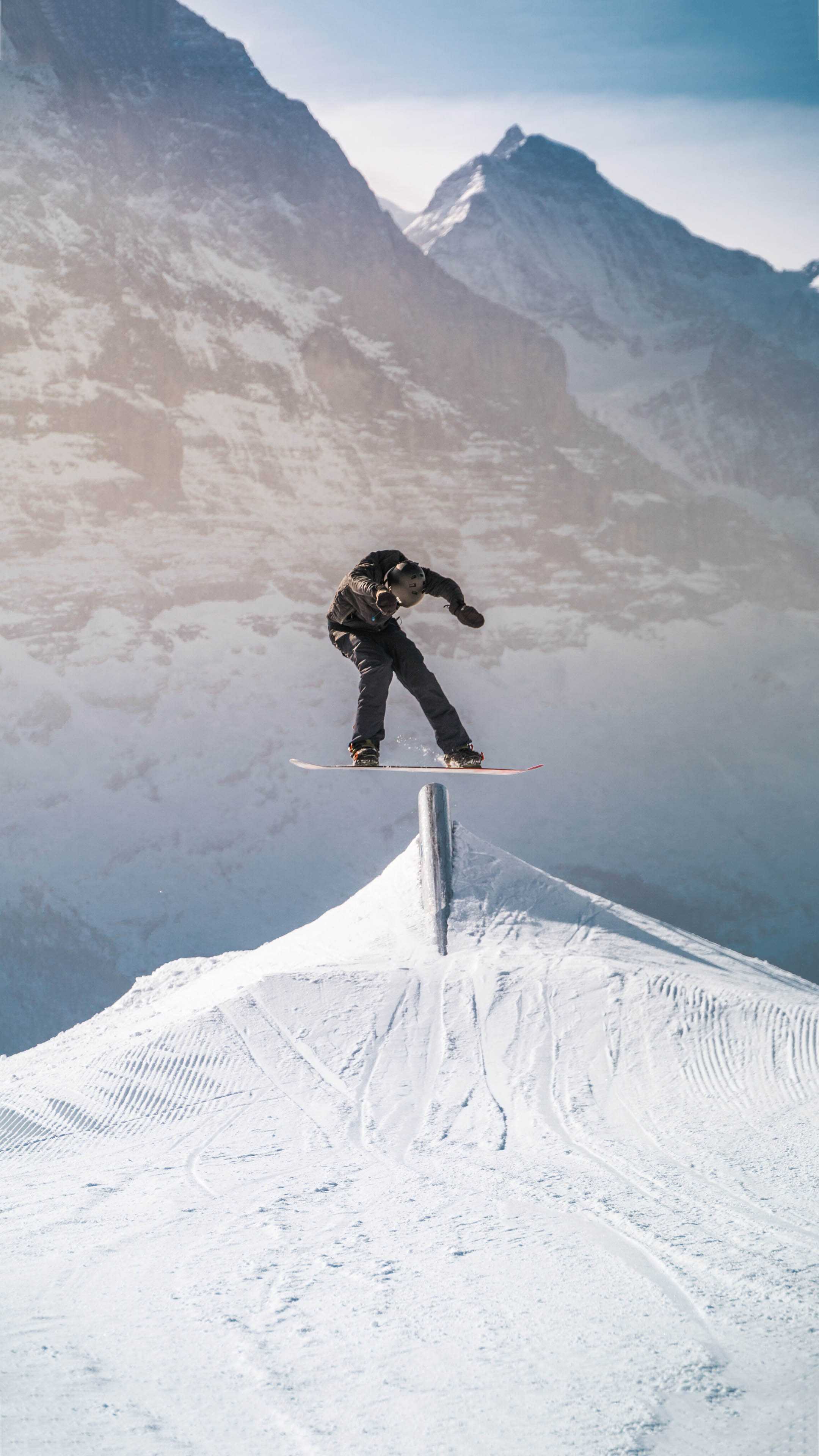 A snowboarder in mid-air after a jump off a snowy mountain - Ski
