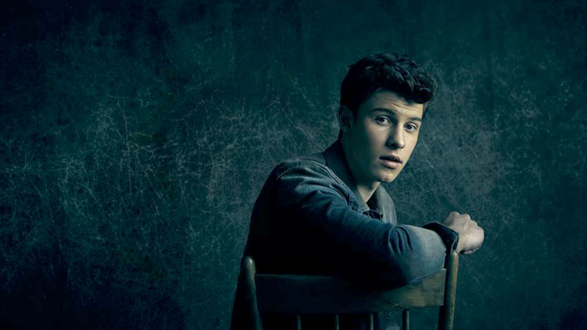 A young man sitting in an empty chair - Shawn Mendes