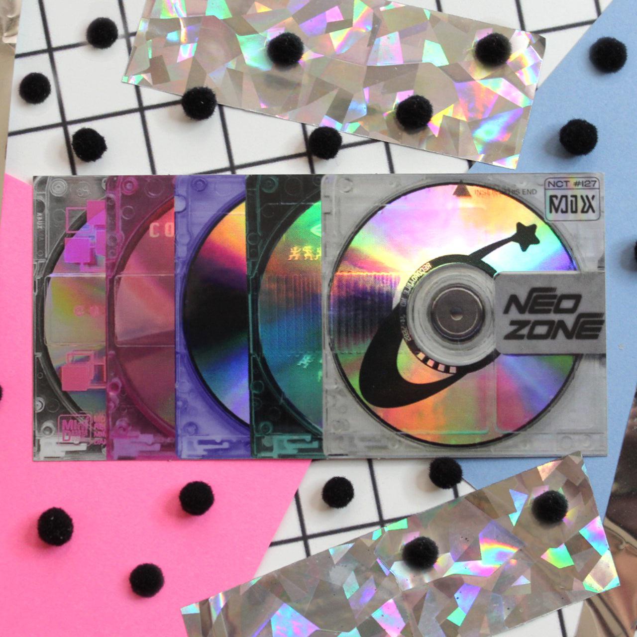 A collection of CDs in varying shades of pink, purple, blue and silver. - Internetcore