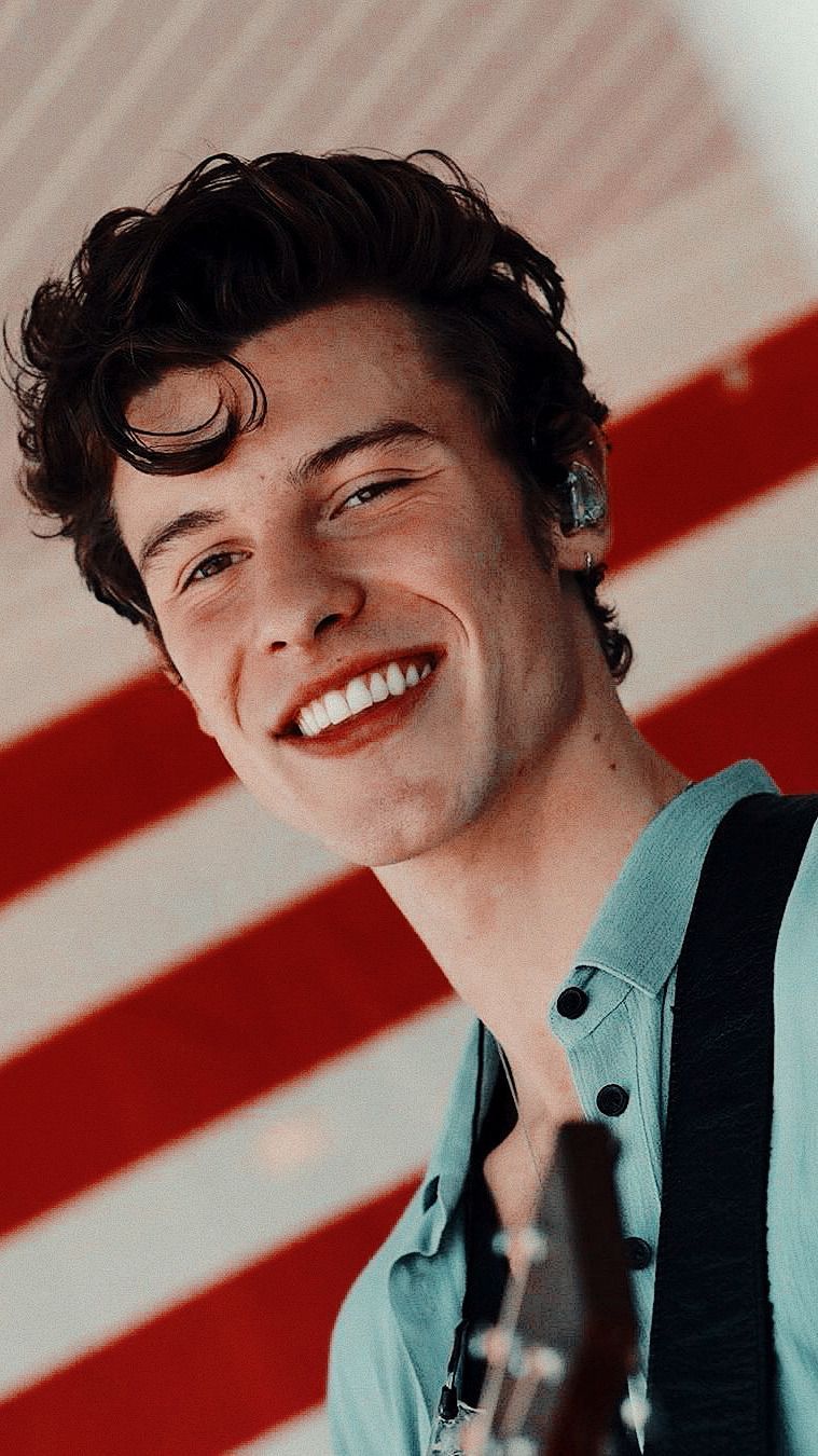 Shawn Mendes smiling in front of an American flag - Shawn Mendes