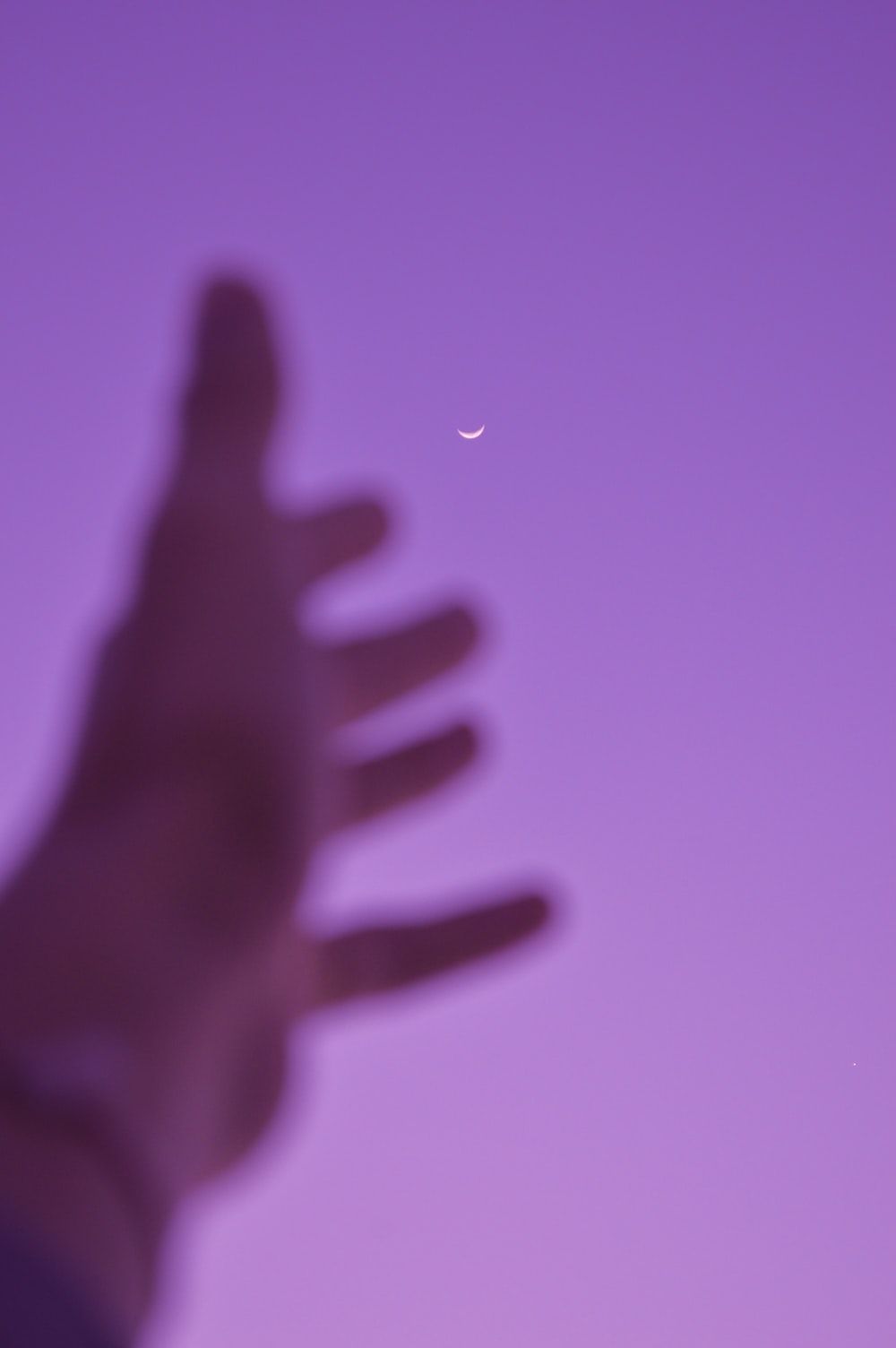 A blurry photo of a person's hand with a half moon in the photo