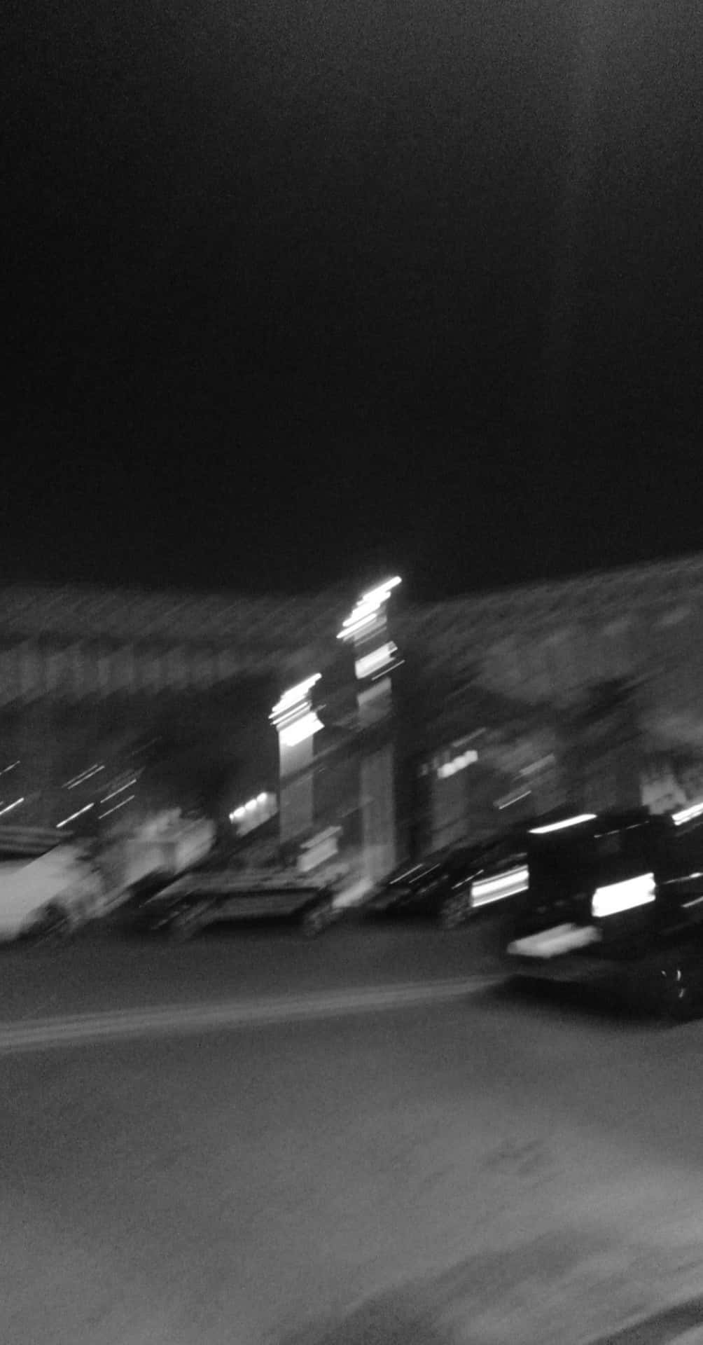 A blurry black and white photo of a building and cars - Blurry