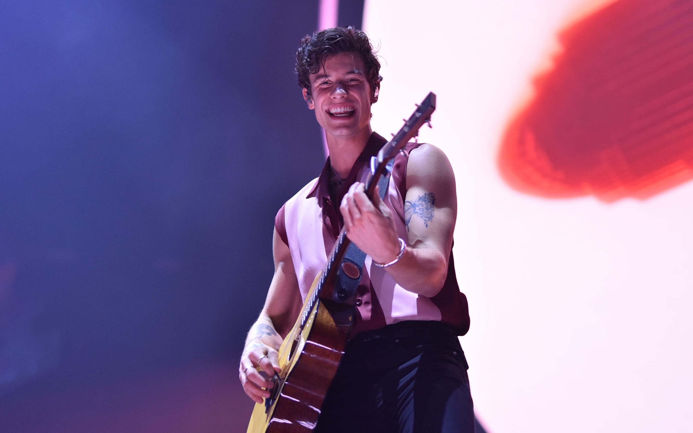 A man playing an acoustic guitar on stage - Shawn Mendes