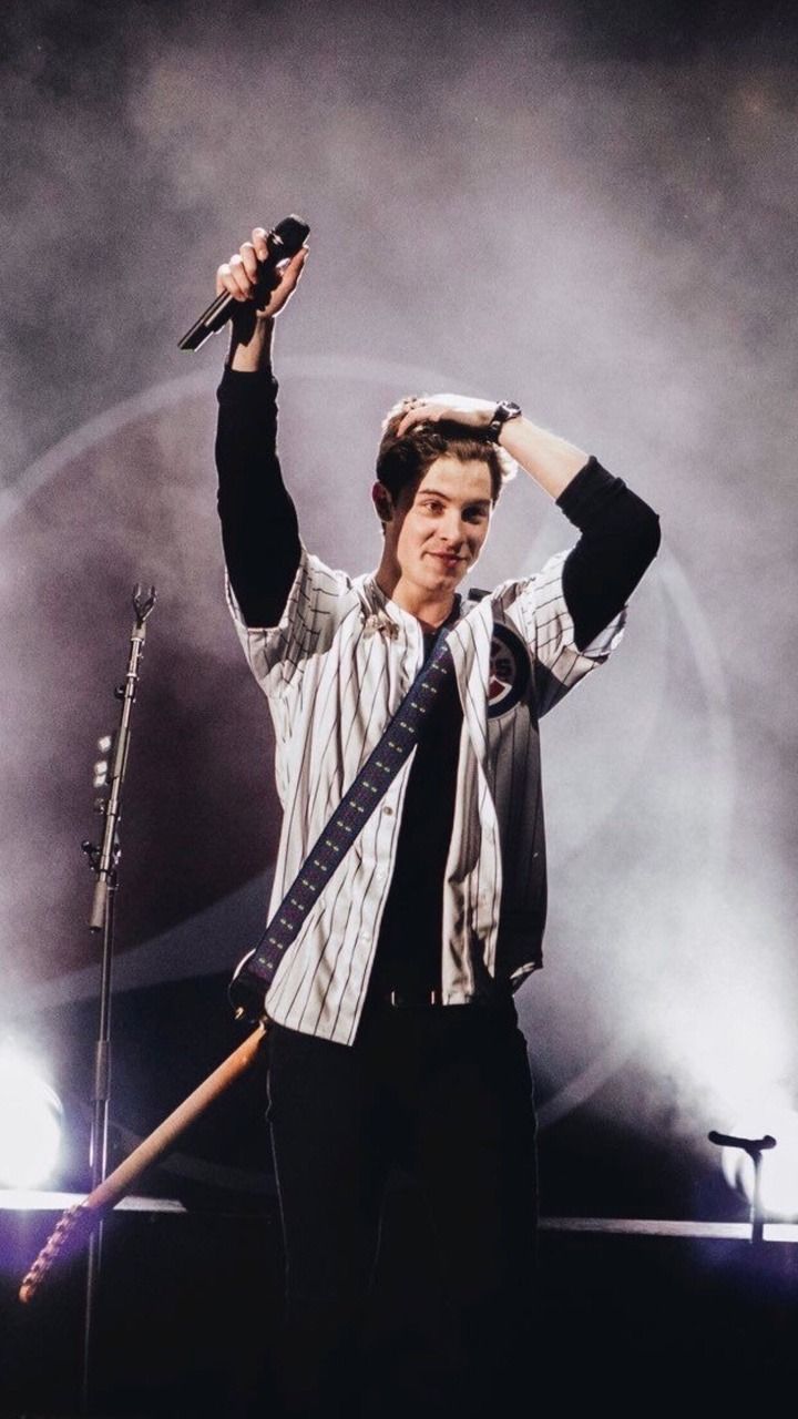 A man holding up his guitar on stage - Shawn Mendes