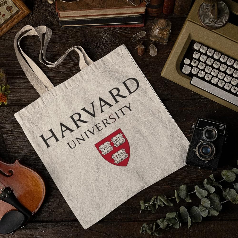 A Harvard tote bag on a table with a typewriter and a violin. - Harvard