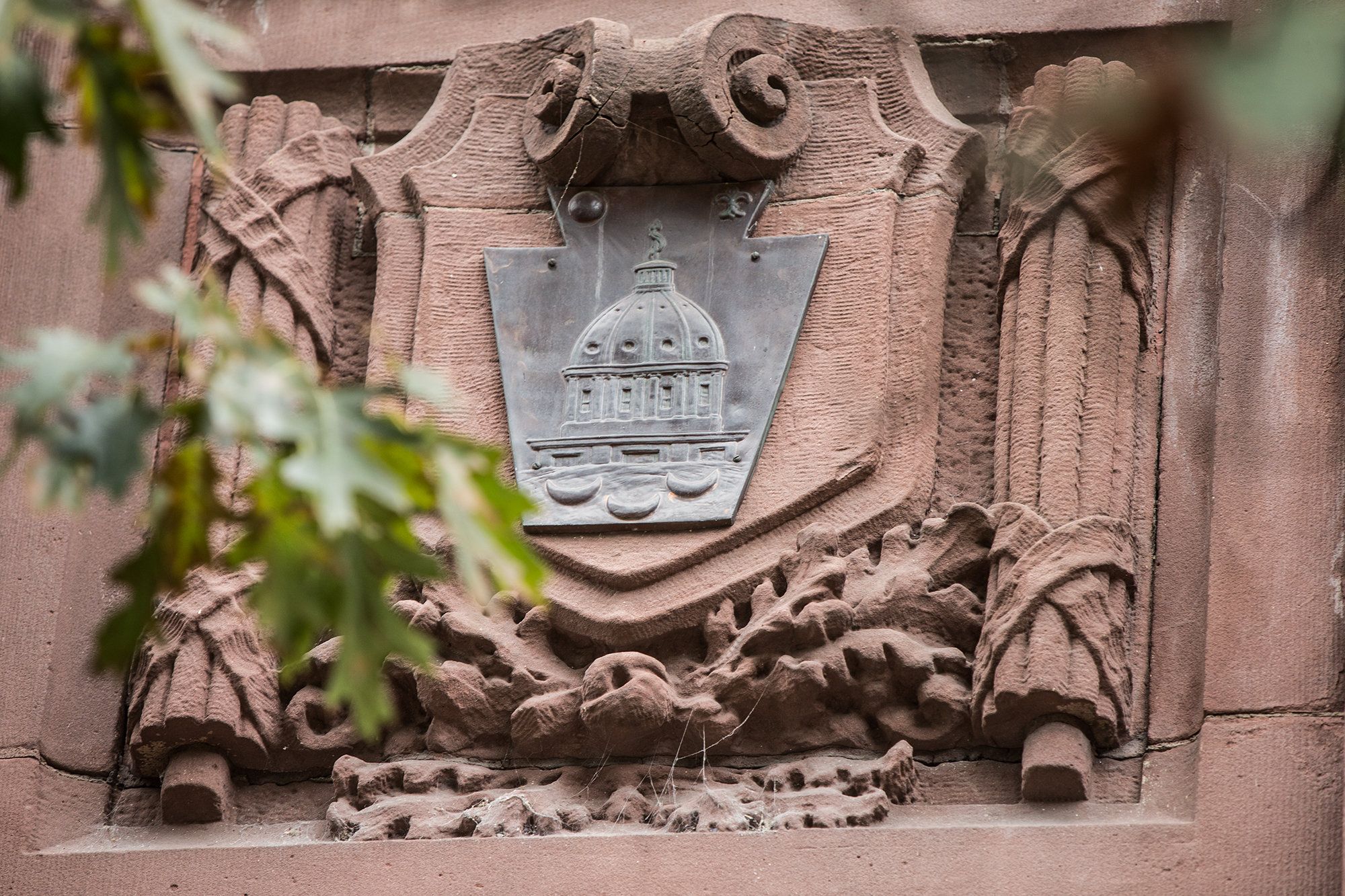 A stone relief of the Capitol building is seen on the side of the statehouse. - Harvard