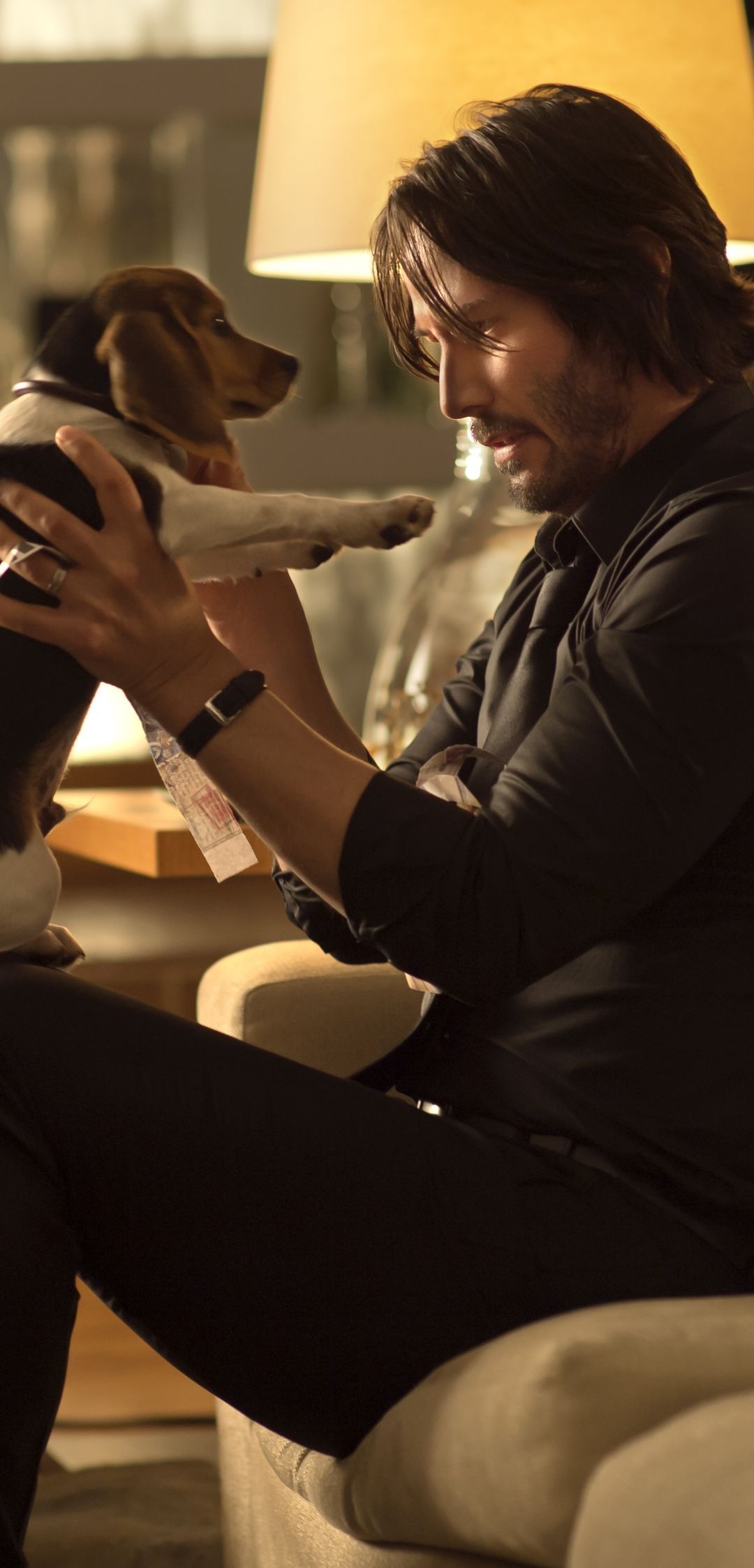 Keanu Reeves sitting on a couch with a dog - John Wick