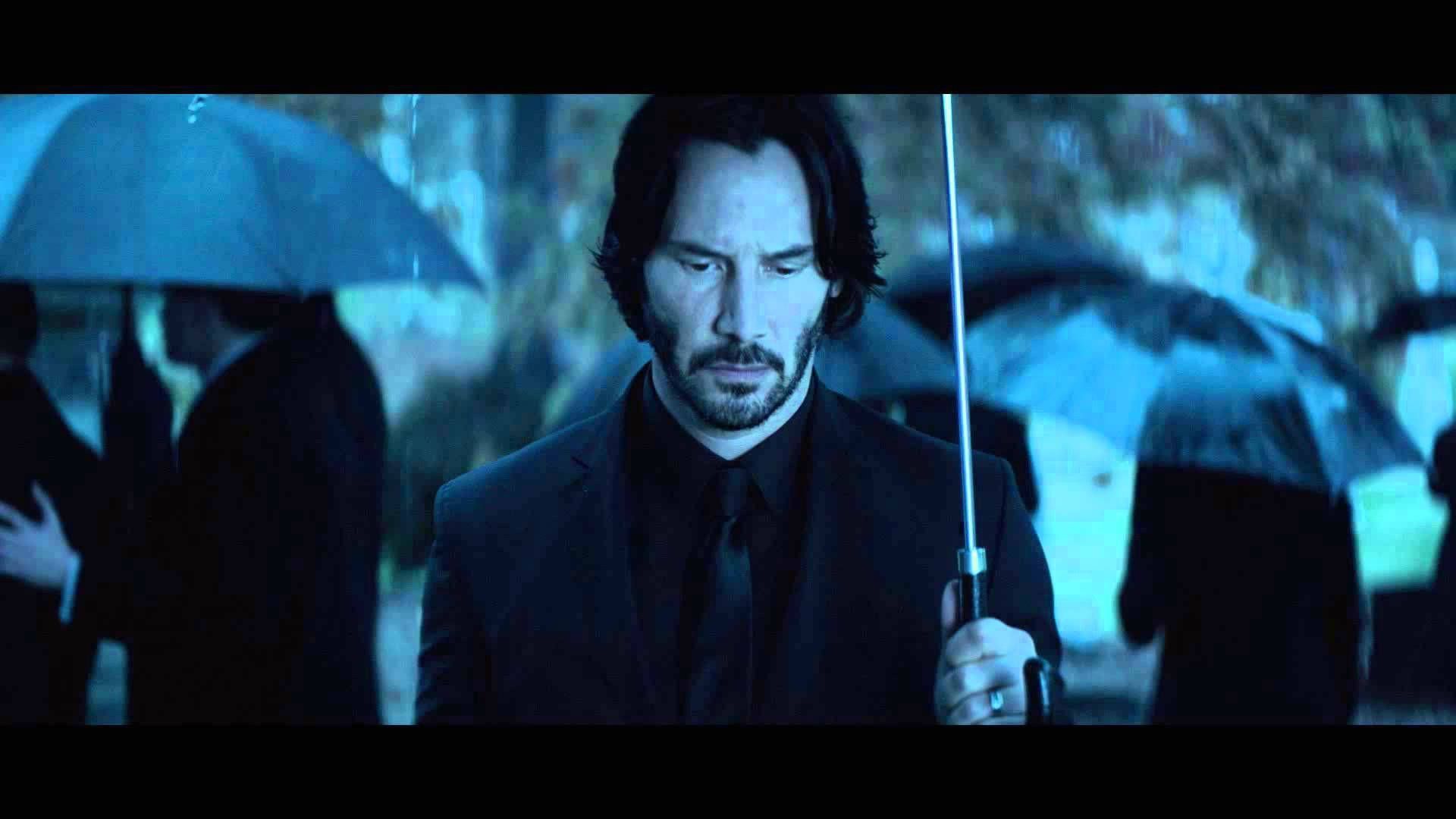 John Wick walks in the rain with a black umbrella - John Wick