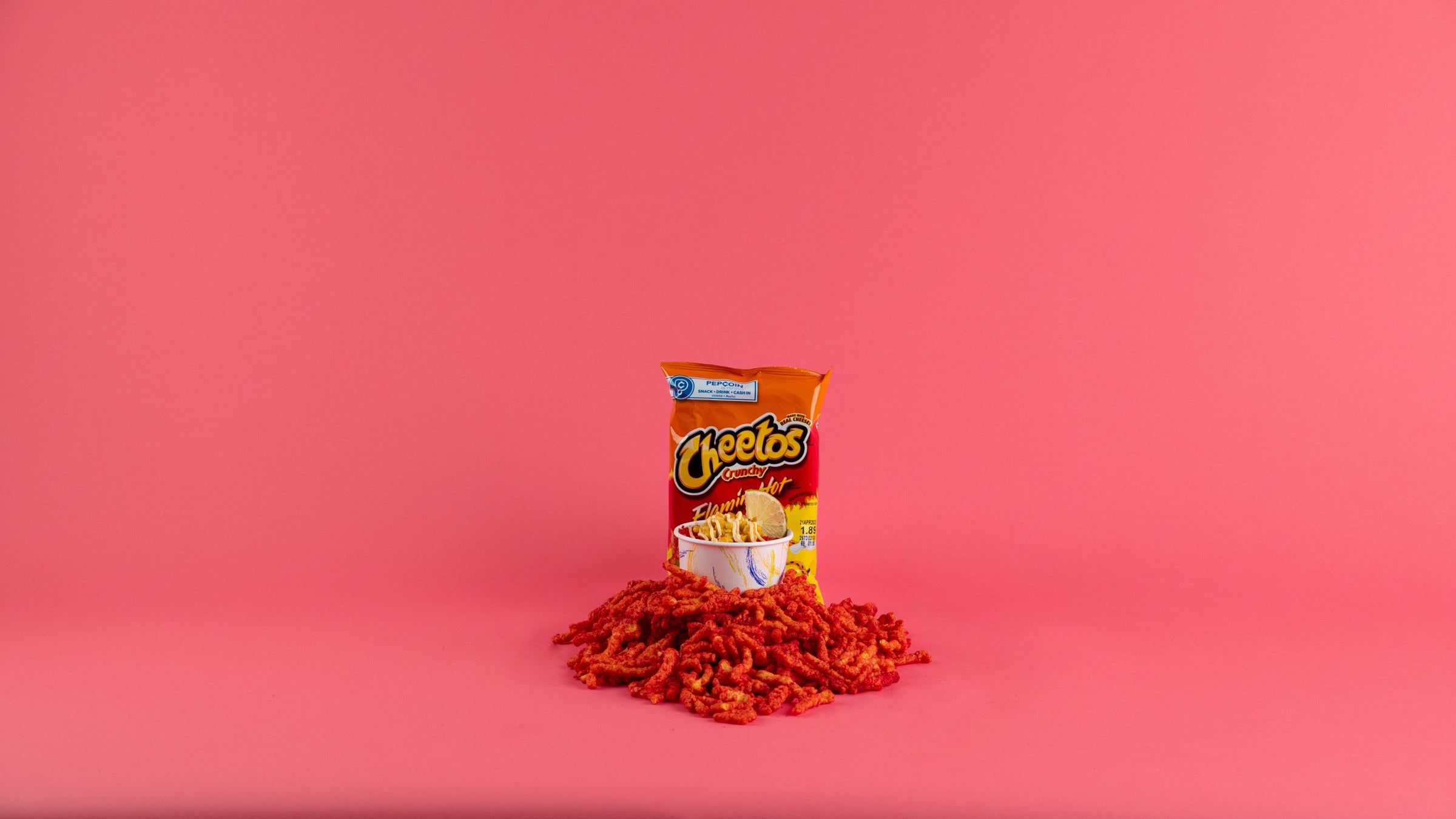 A bag of Fritos corn chips on a pink background - Cheetos