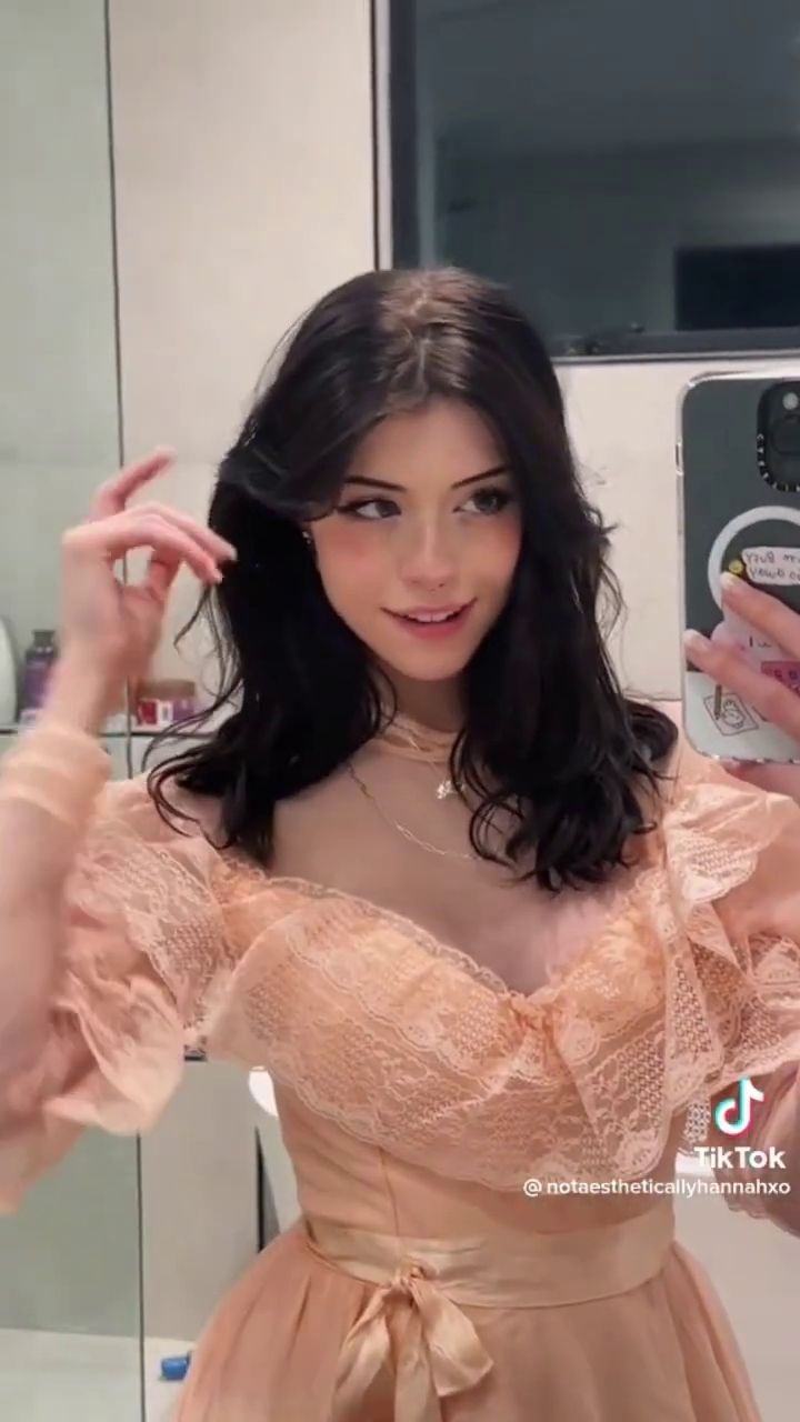 This is a video of a woman taking a mirror selfie in a pink dress. - Hannah OwO