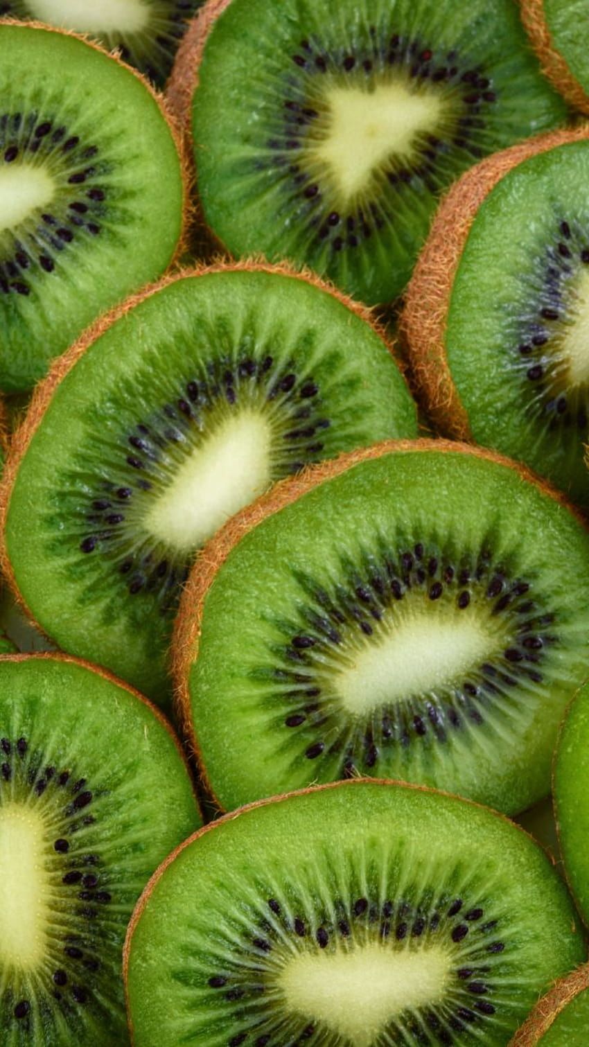 A close up of kiwi slices, with the seeds visible in the middle of each. - Kiwi