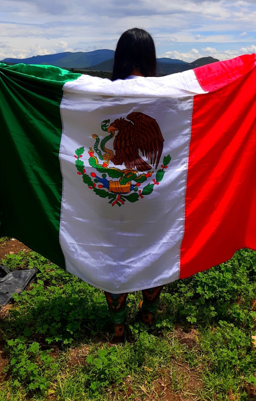 A woman holding a Mexican flag in front of her body - Mexico