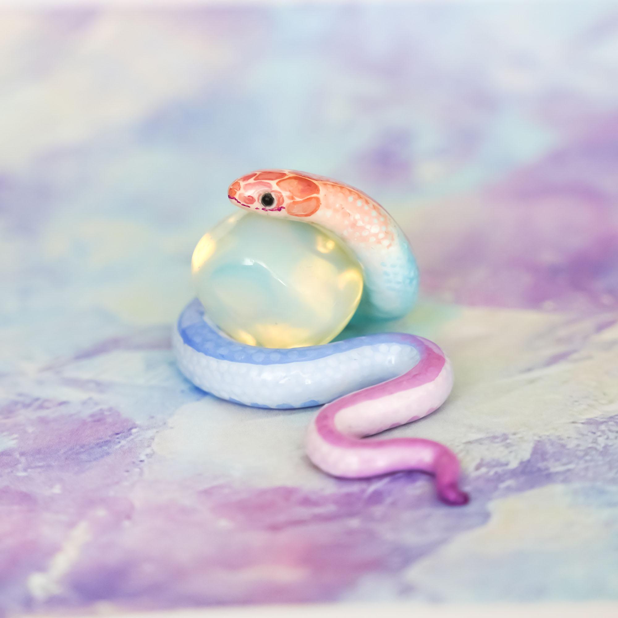 A pink and blue snake toy with a ball in its mouth - Snake