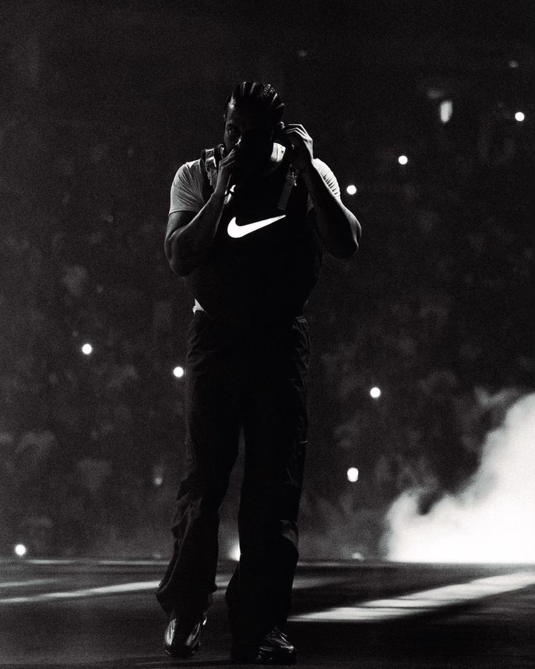 Travis Scott wearing a white shirt and black pants with a Nike logo on it - Drake