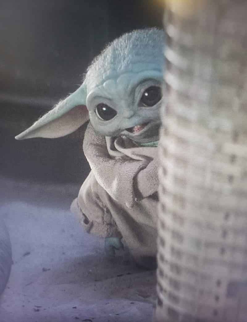A baby Yoda plush toy is shown in a close-up. - Baby Yoda