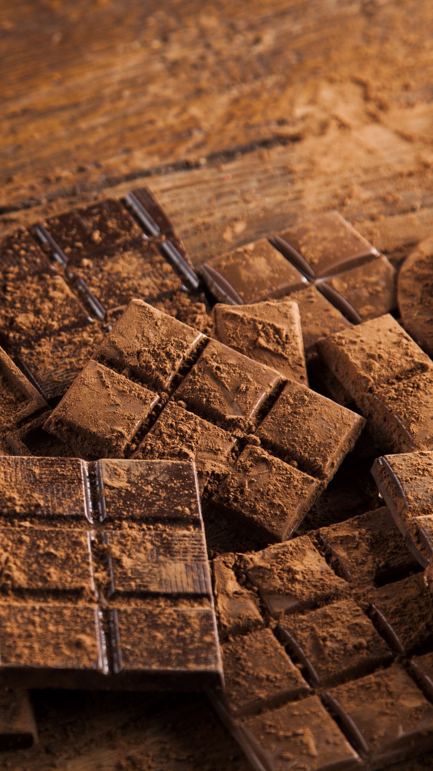 A pile of chocolate bars on a wooden table. - Chocolate