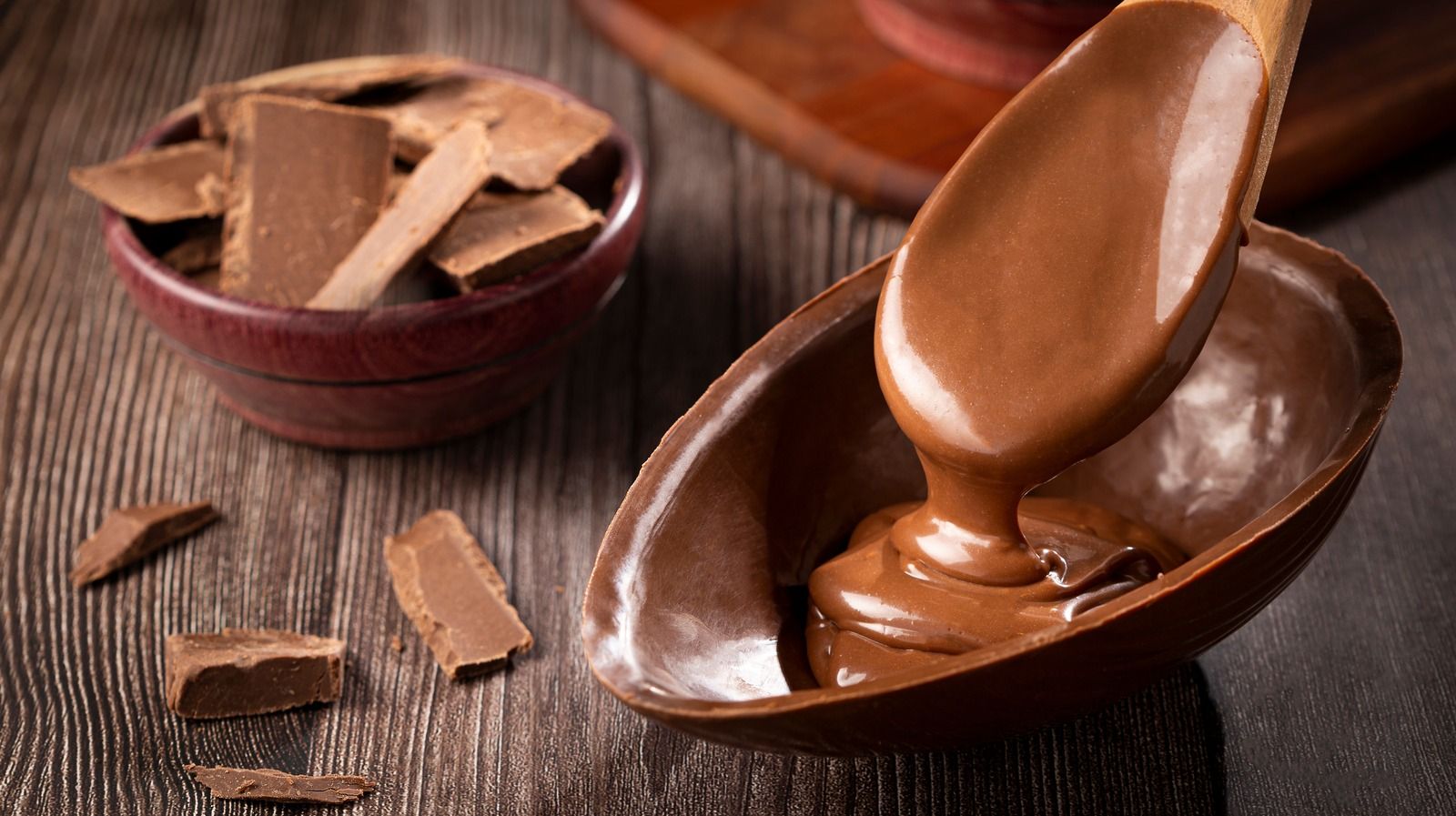 A bowl of melted chocolate with a spoon in it. - Chocolate