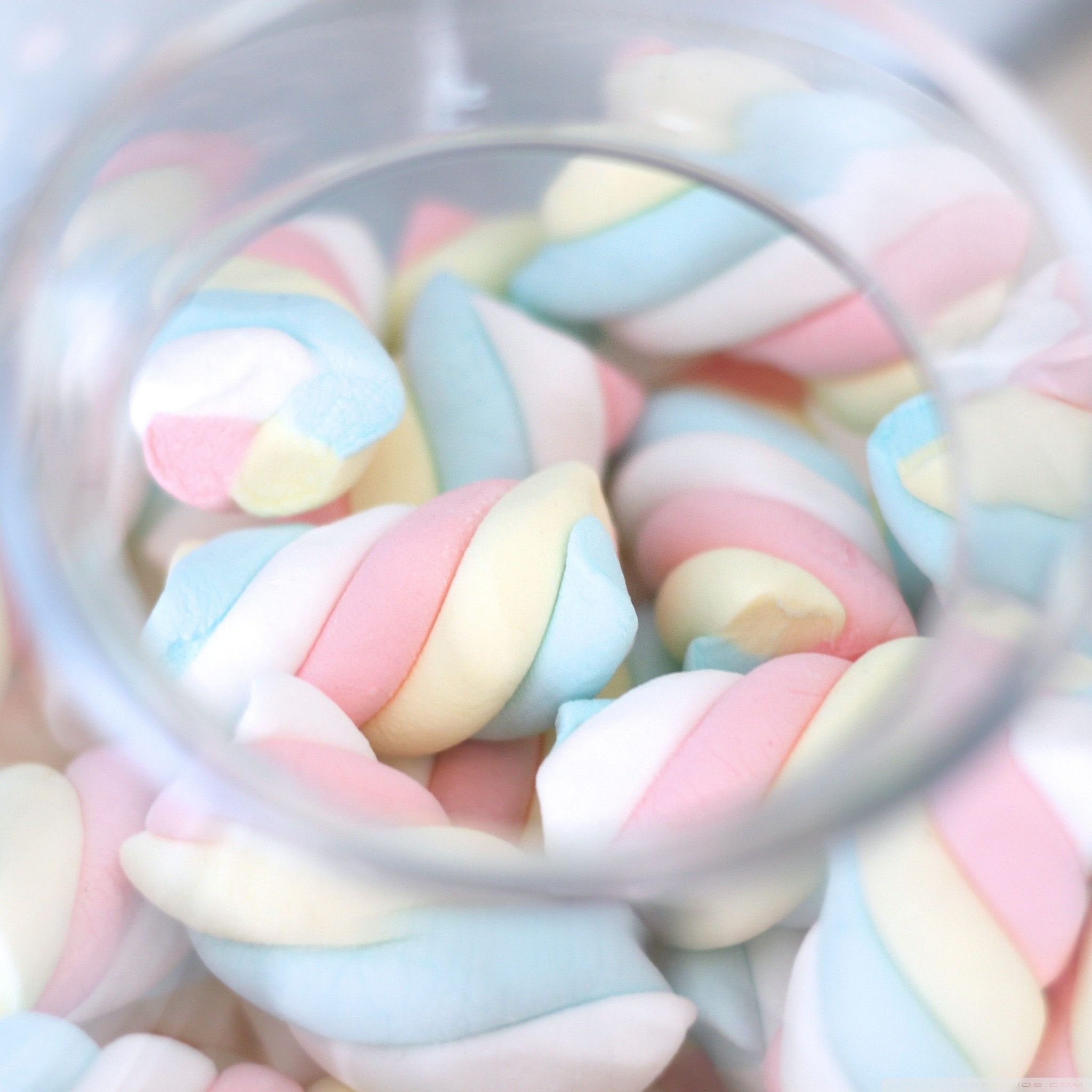 A glass jar filled with pastel colored marshmallows. - Marshmallows