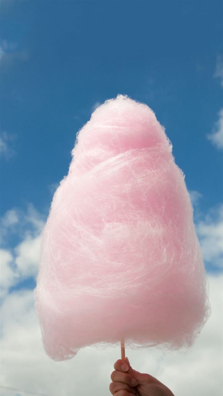 A hand holding a pink cotton candy against a blue sky - Marshmallows