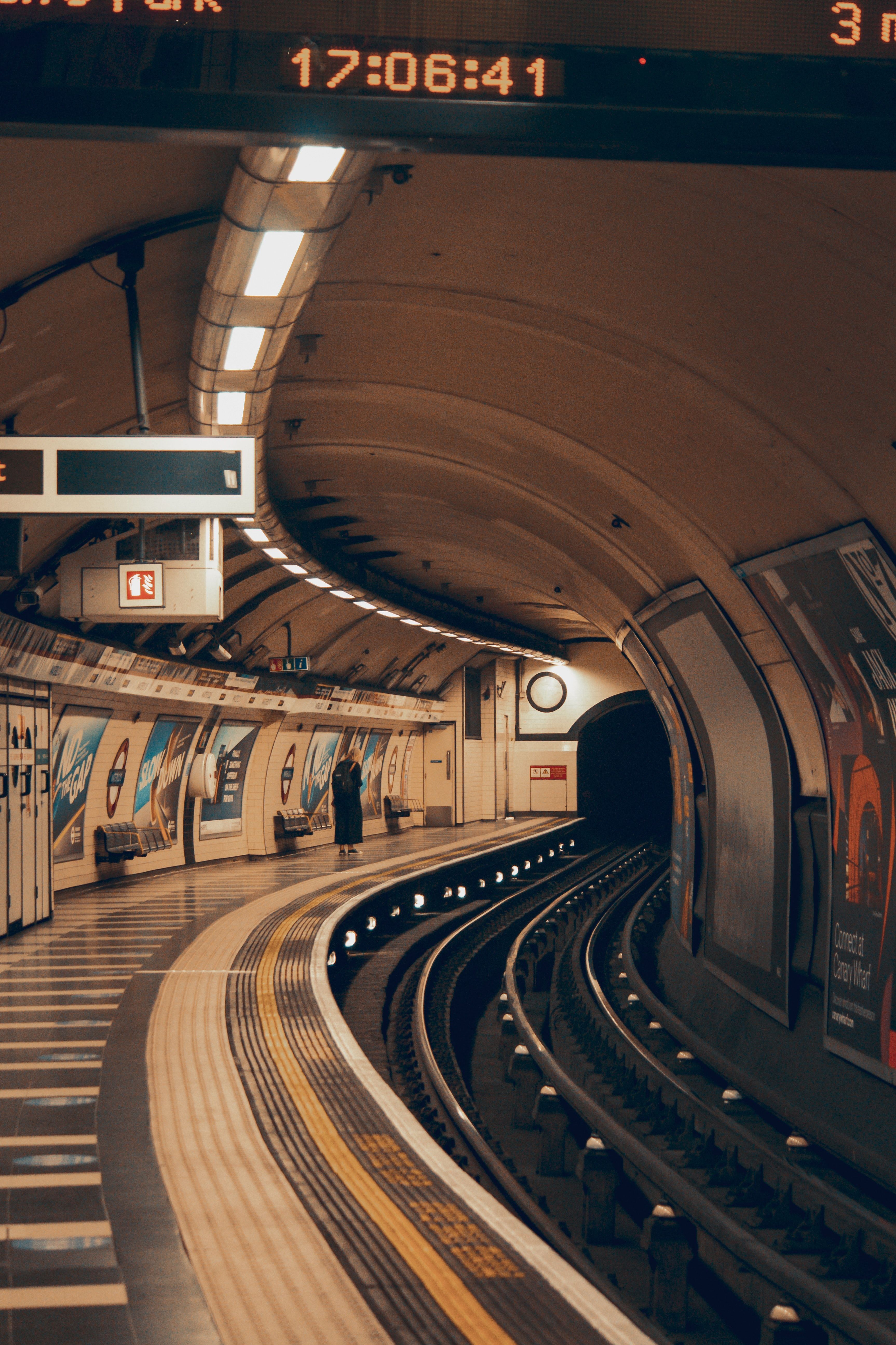 A woman stands on a platform in a dimly lit underground station. - London