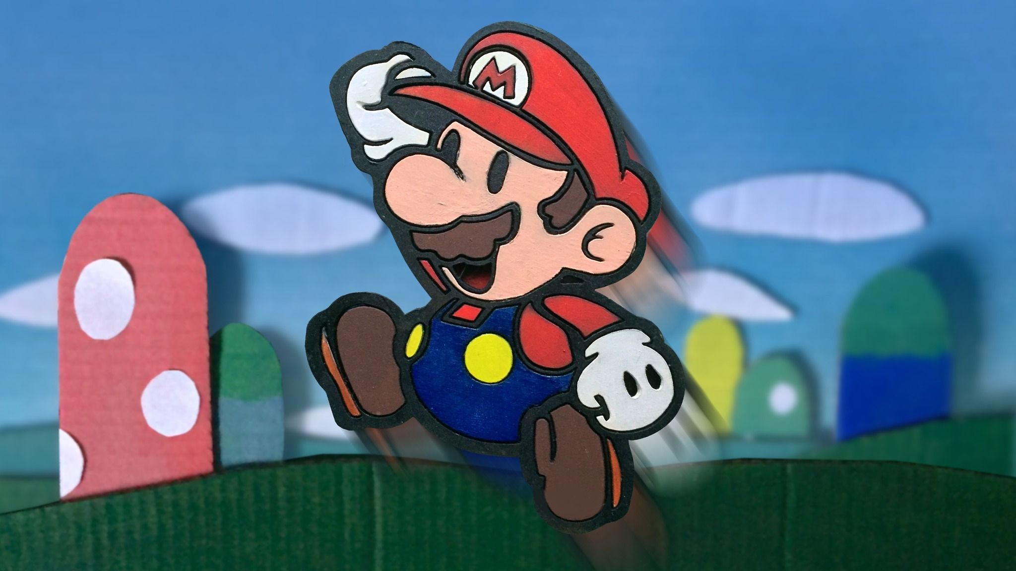 A paper Mario figure standing in front of a paper mushroom and a paper pipe. - Super Mario