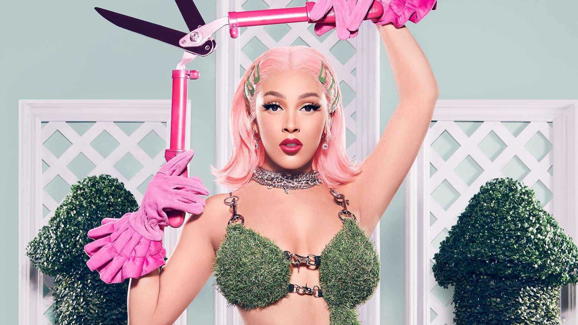Cardi B in a moss bra and pink gloves holding pink pruning shears - Doja Cat