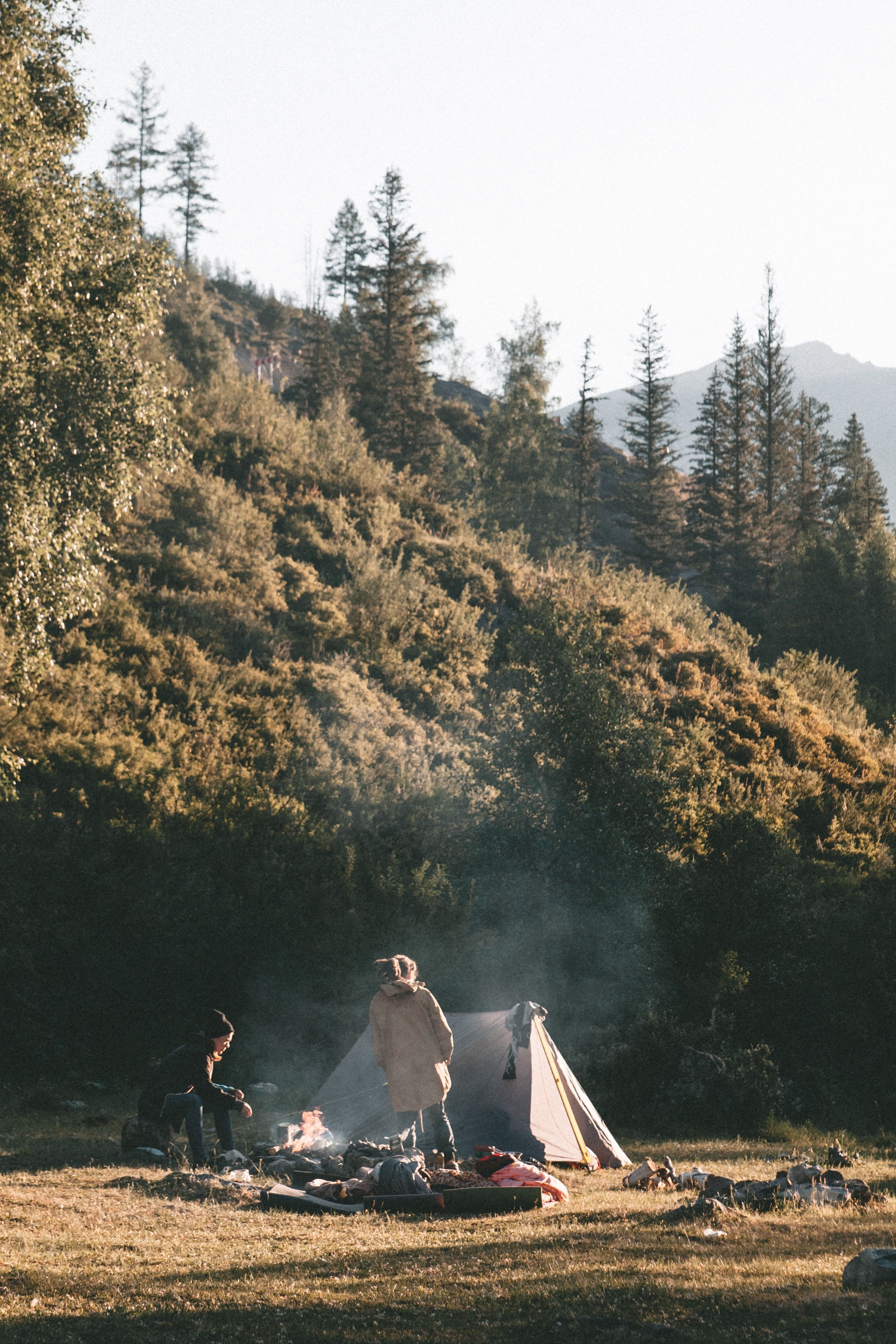 A couple enjoys a cozy campfire in the mountains, surrounded by trees and a beautiful landscape. | Photography by @jamesonmerritt | #camping #mountains #outdoors #photography - Camping