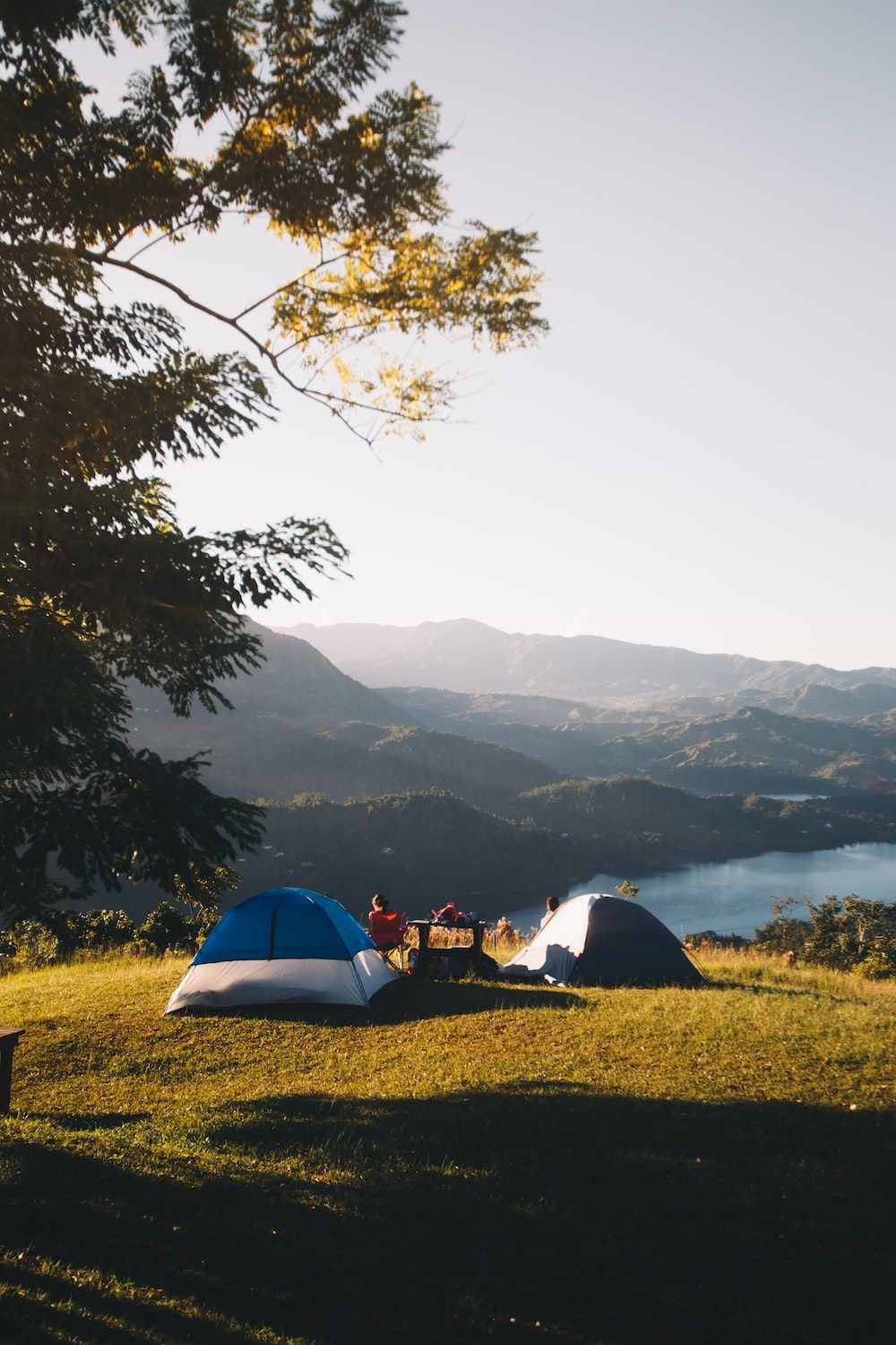 Two tents pitched on a hillside overlooking a lake - Camping