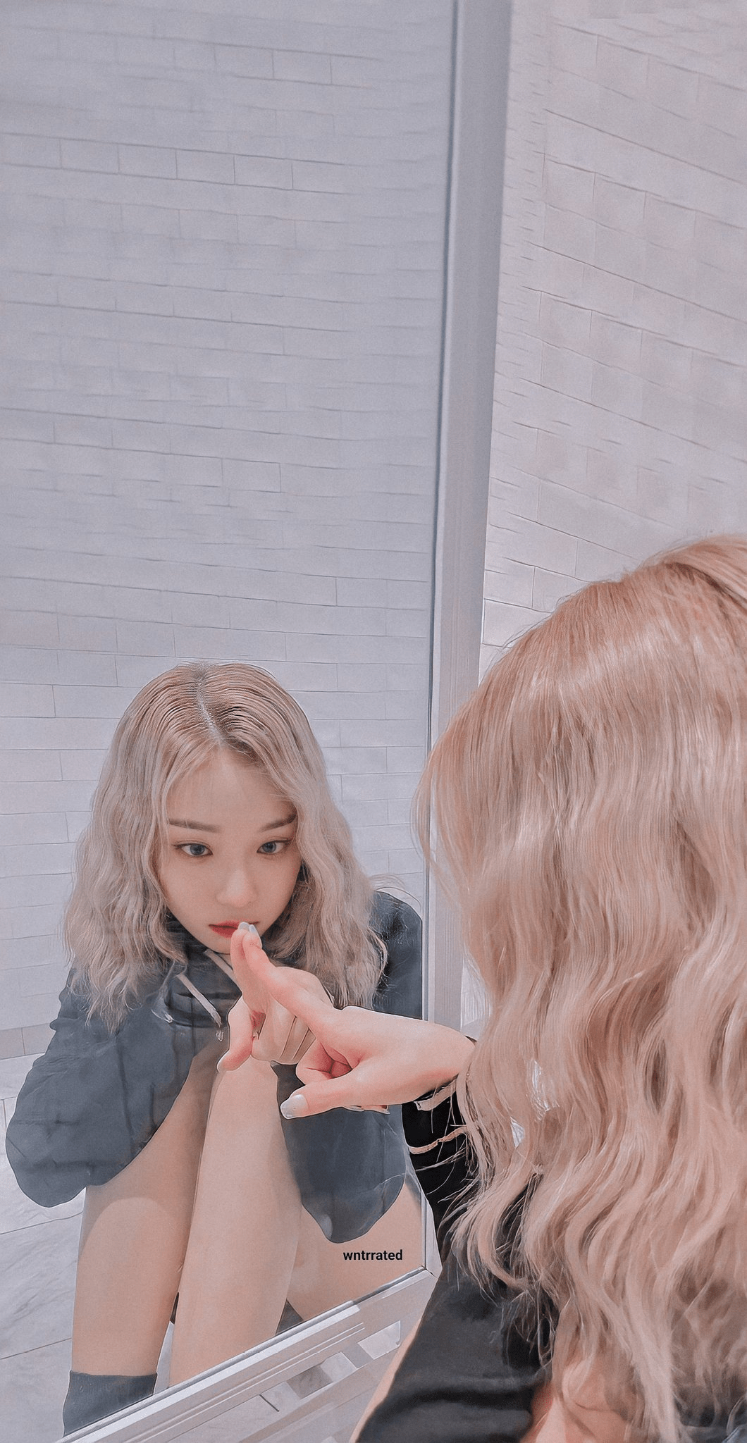 A woman with blonde hair looking at her reflection in a mirror. - Aespa
