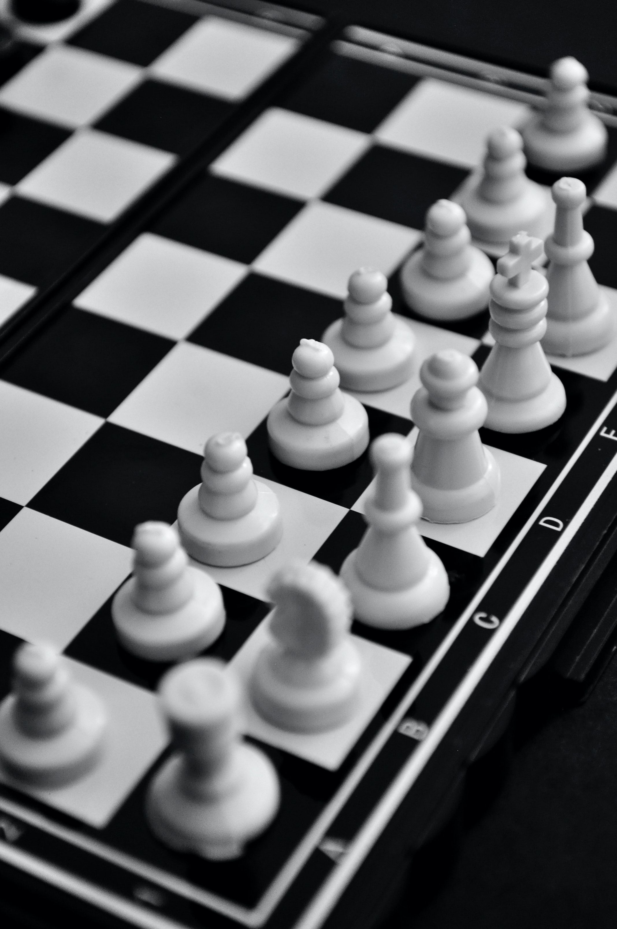 A black and white chessboard with a group of chess pieces on it. - Chess