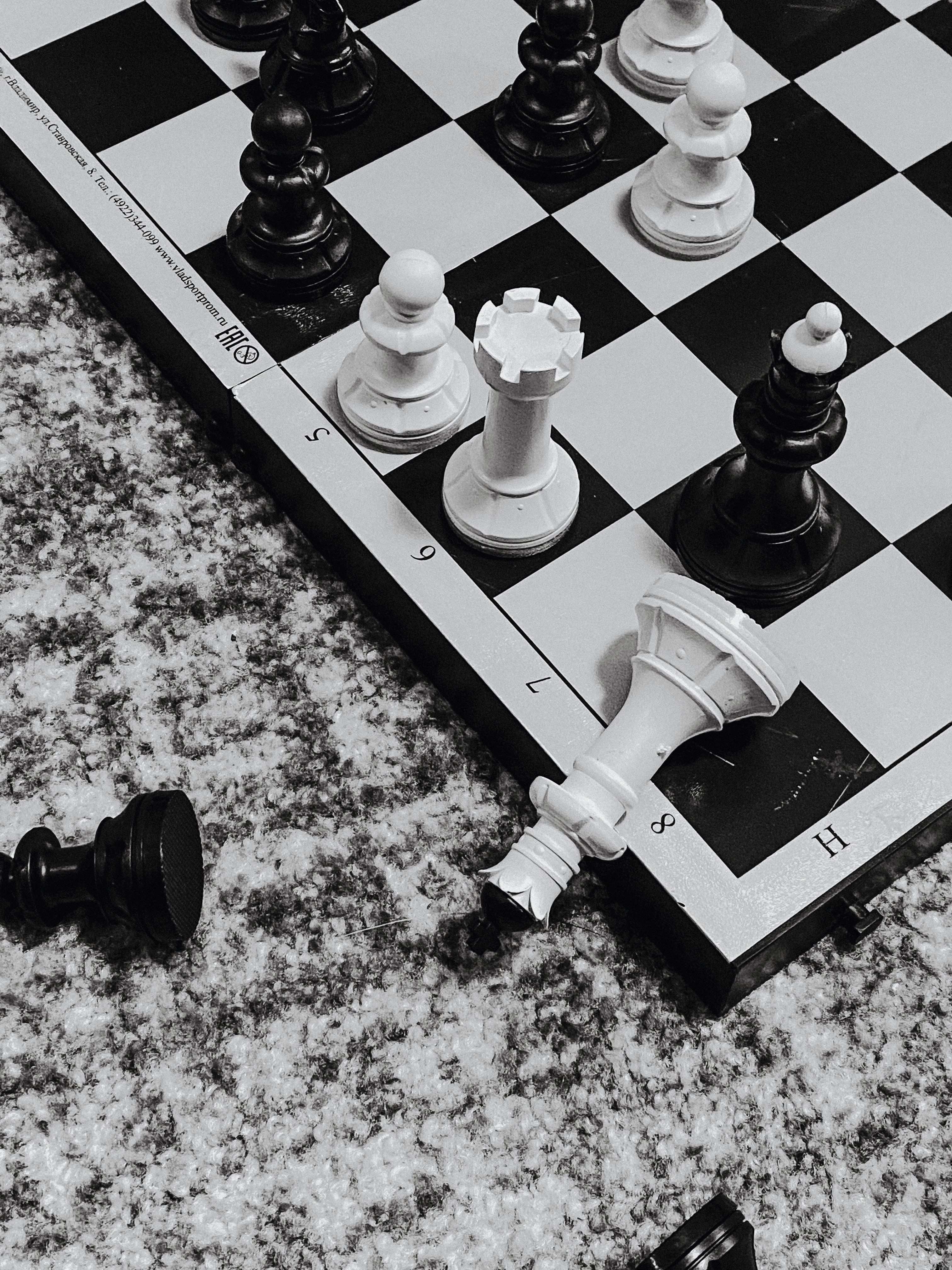A chessboard with pieces on it, including a knight and a bishop, and a fallen pawn. - Chess