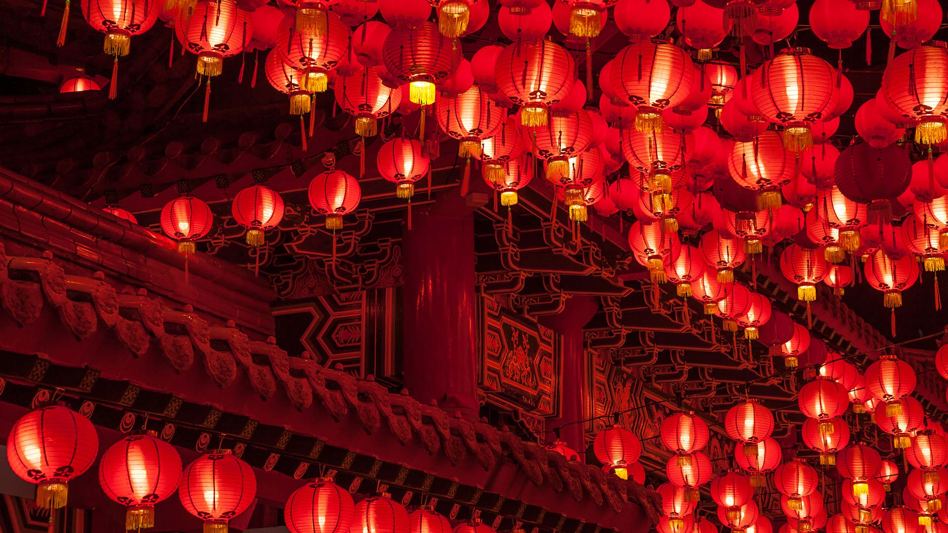 Red lanterns hanging from the ceiling of a building. - Chinese
