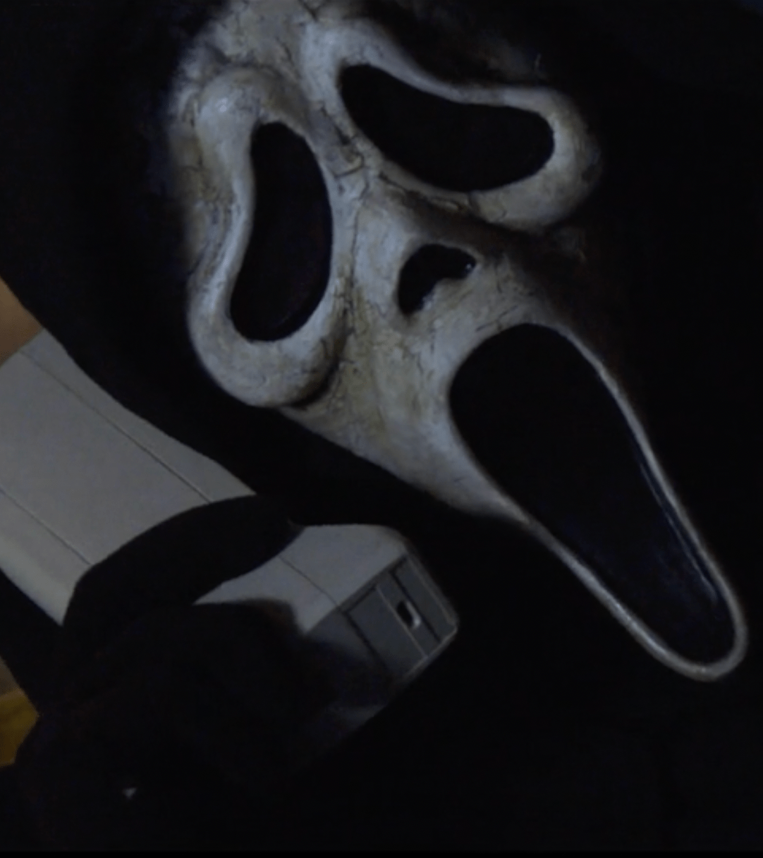 A scream mask is hanging on a door knob. - Ghostface