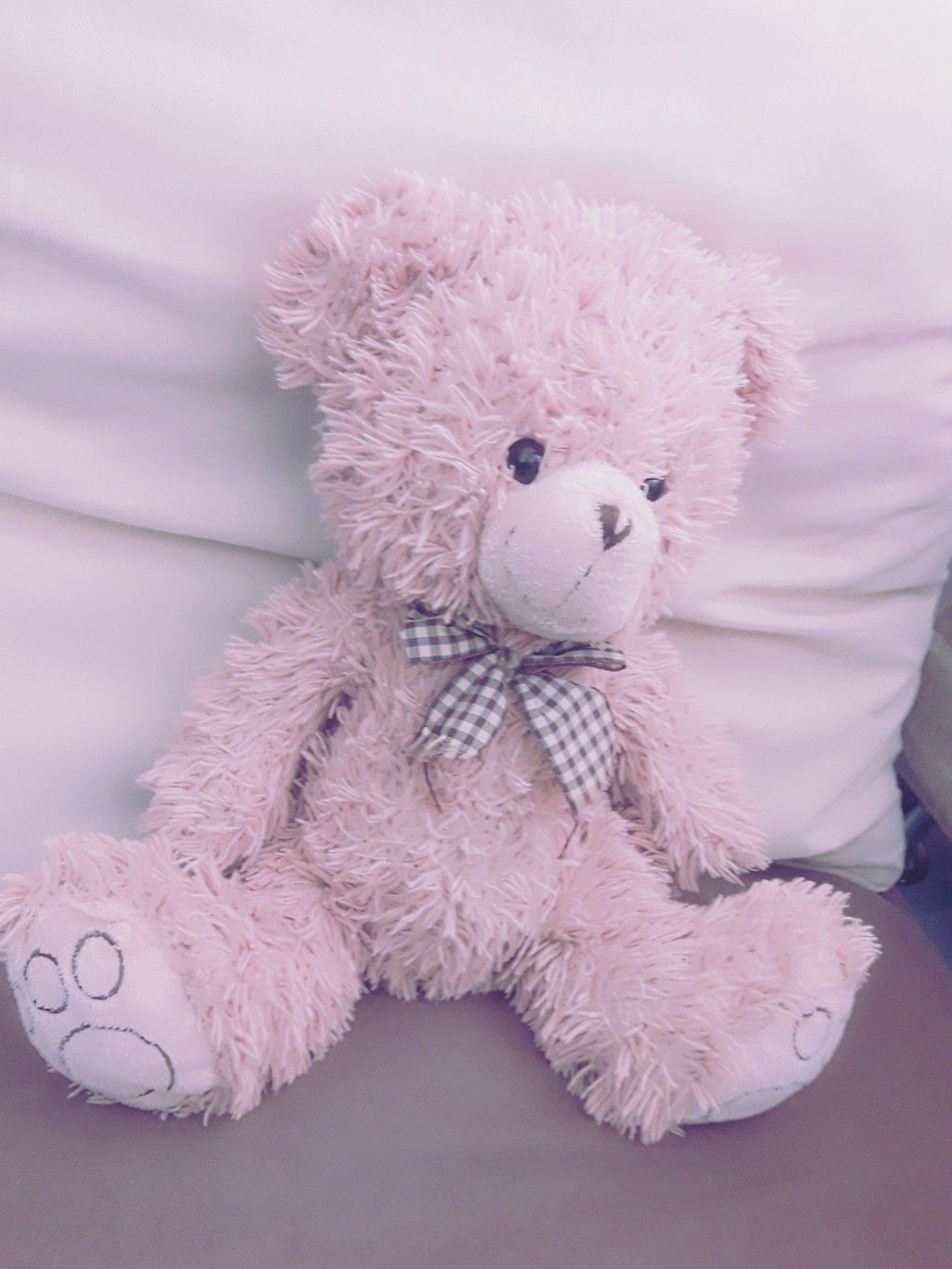 A pink teddy bear sitting on a bed. - Teddy bear