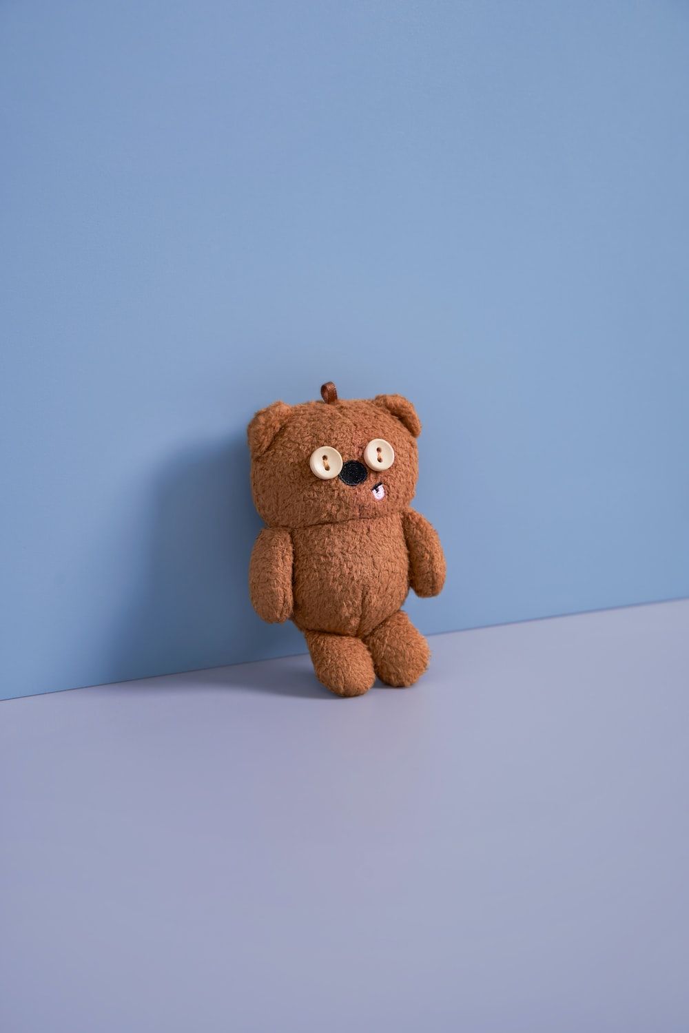 A brown teddy bear with a white button nose and big, round white eyes. - Teddy bear