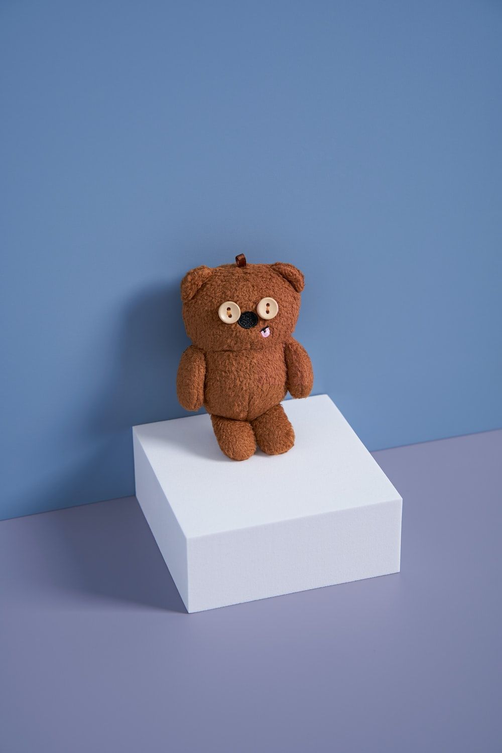 A brown teddy bear sitting on top of a white box photo