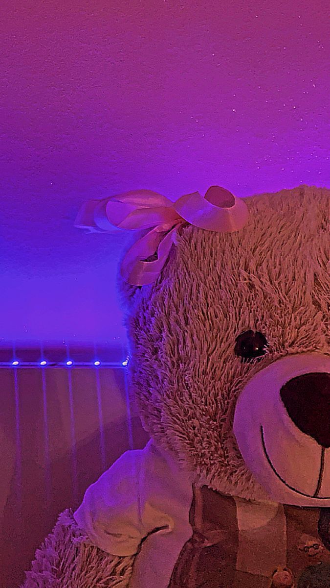 A teddy bear with a bow in a purple room - Teddy bear